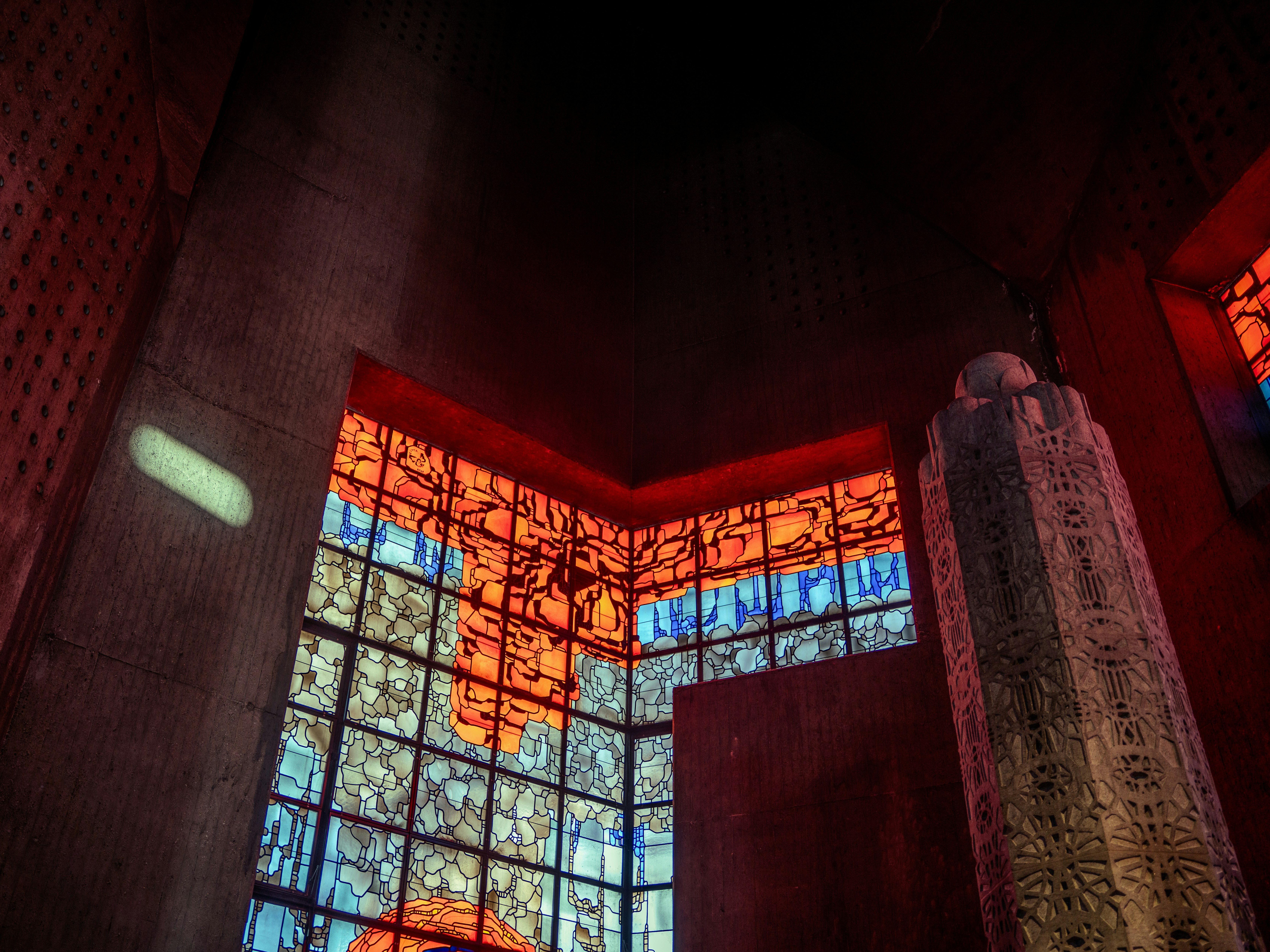 幾何学模様のステンドグラスの窓が高い石造りの建物を照らしています。