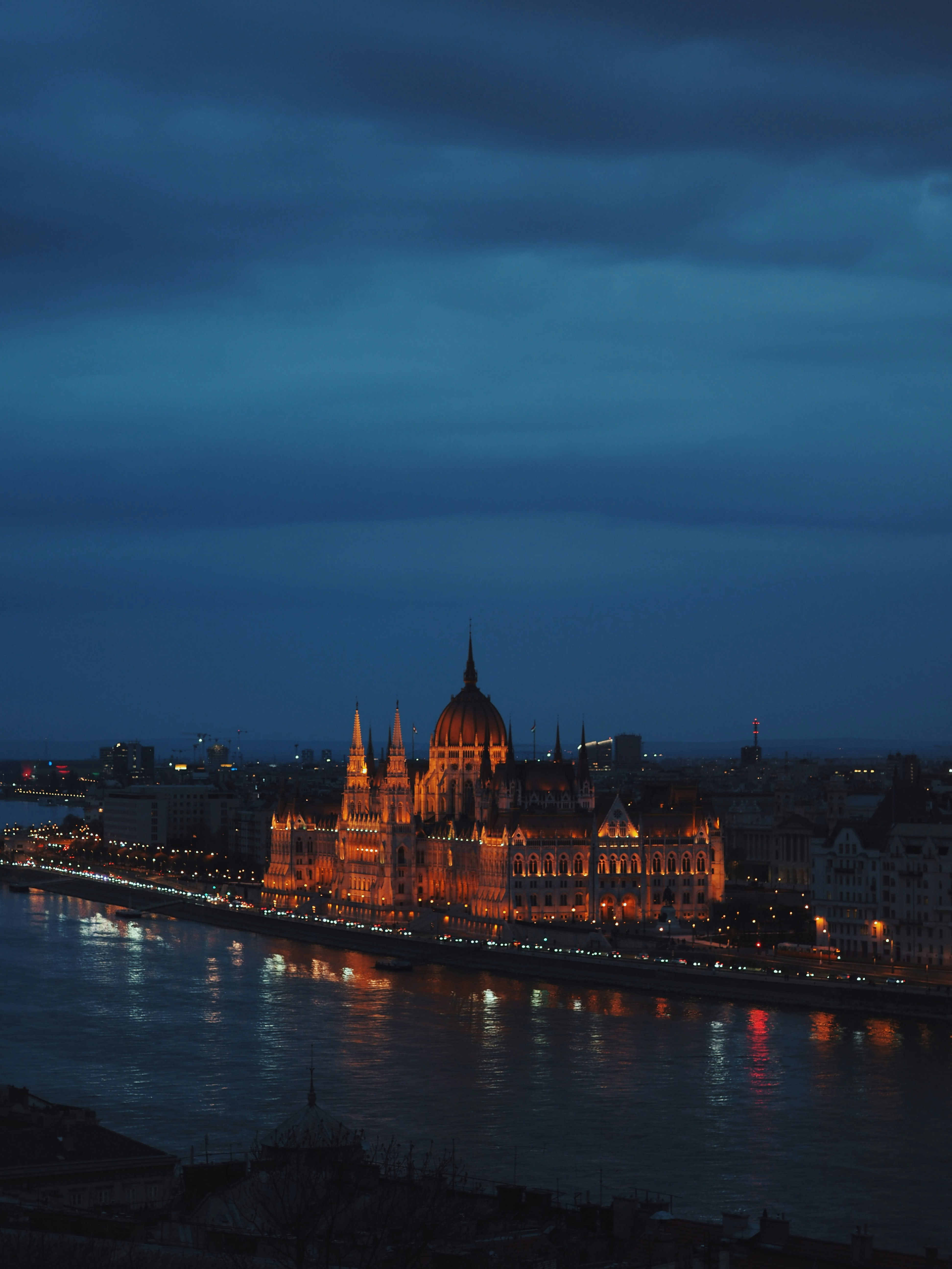 Illuminated parliament building on river at dusk