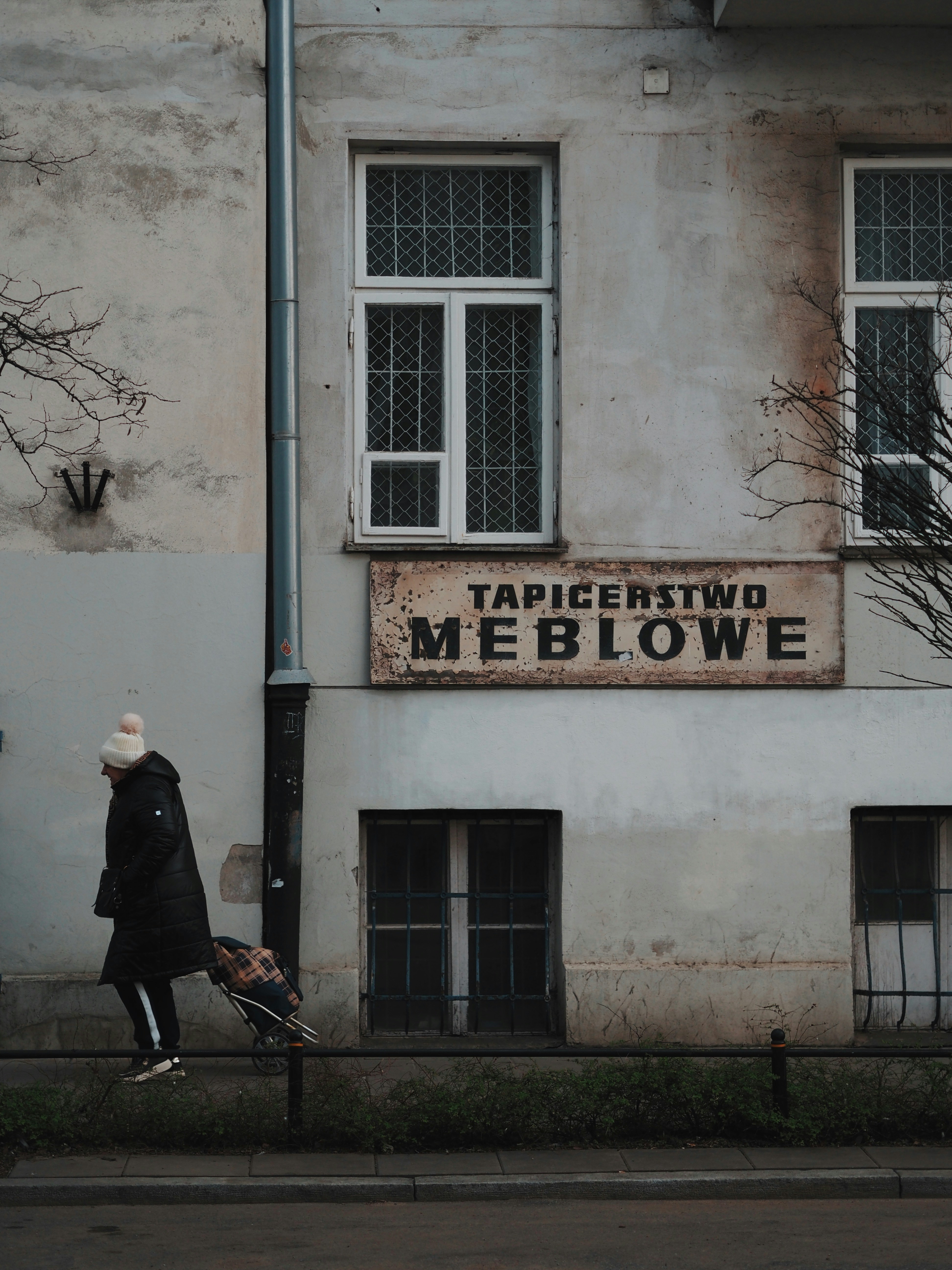 Person walks past a building with old signage.