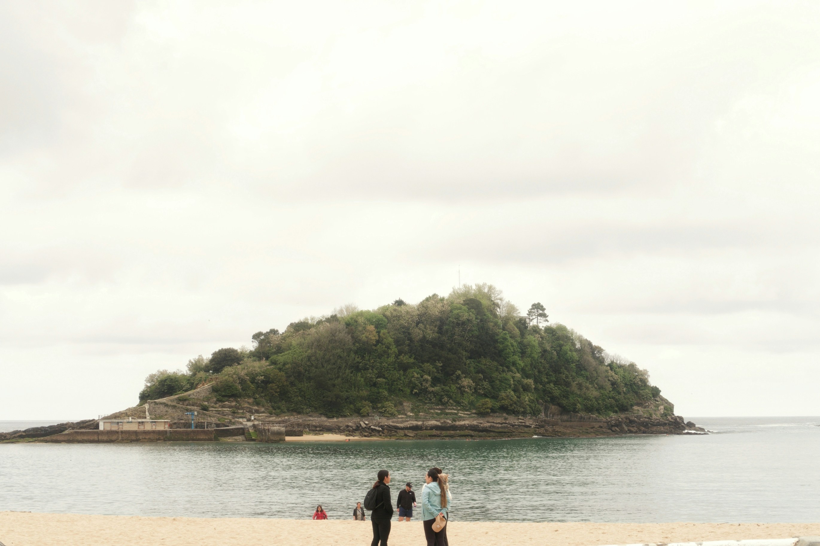 Two people stand on a promenade overlooking an island