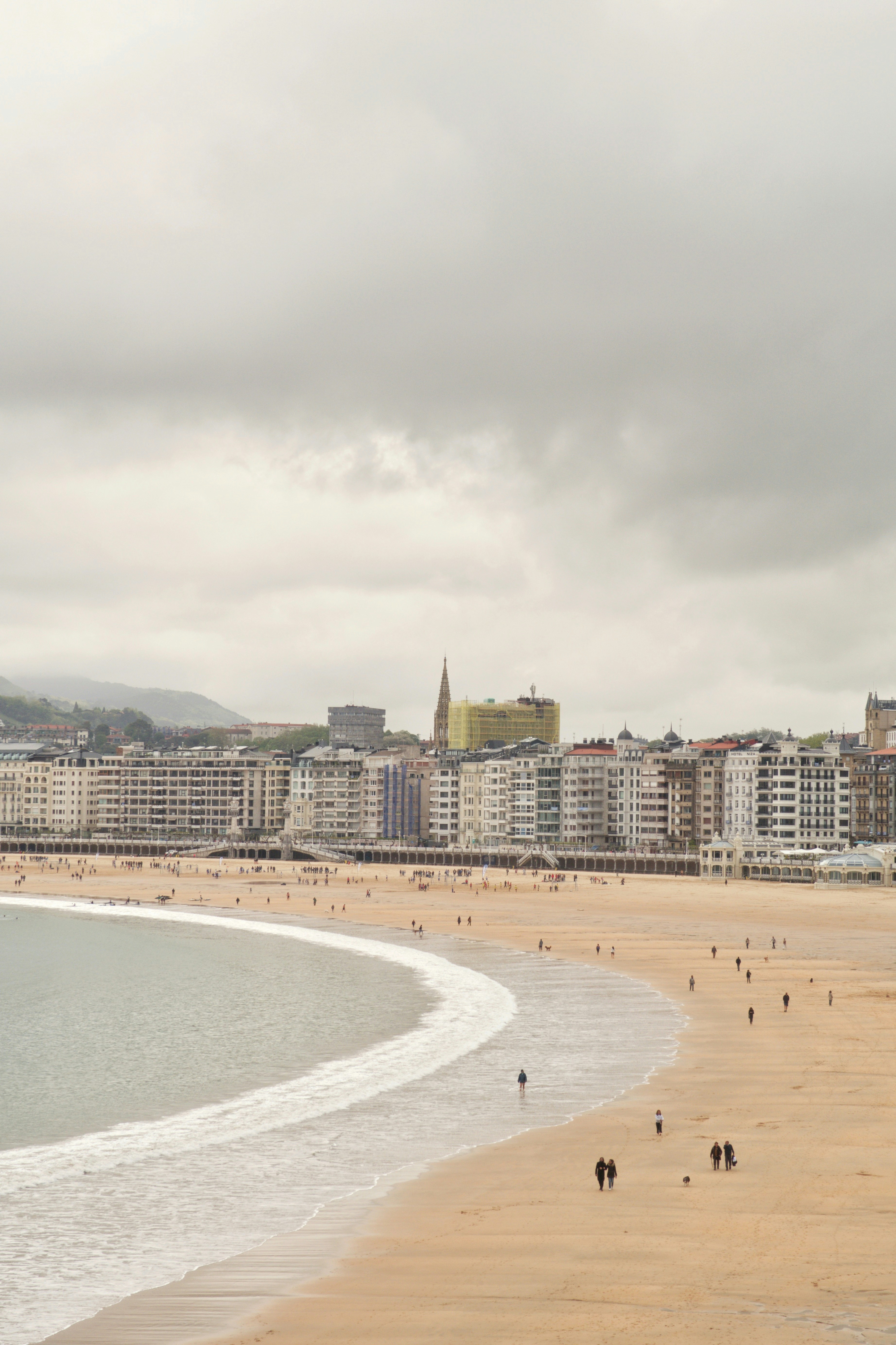 City buildings line a sandy beach with gentle waves