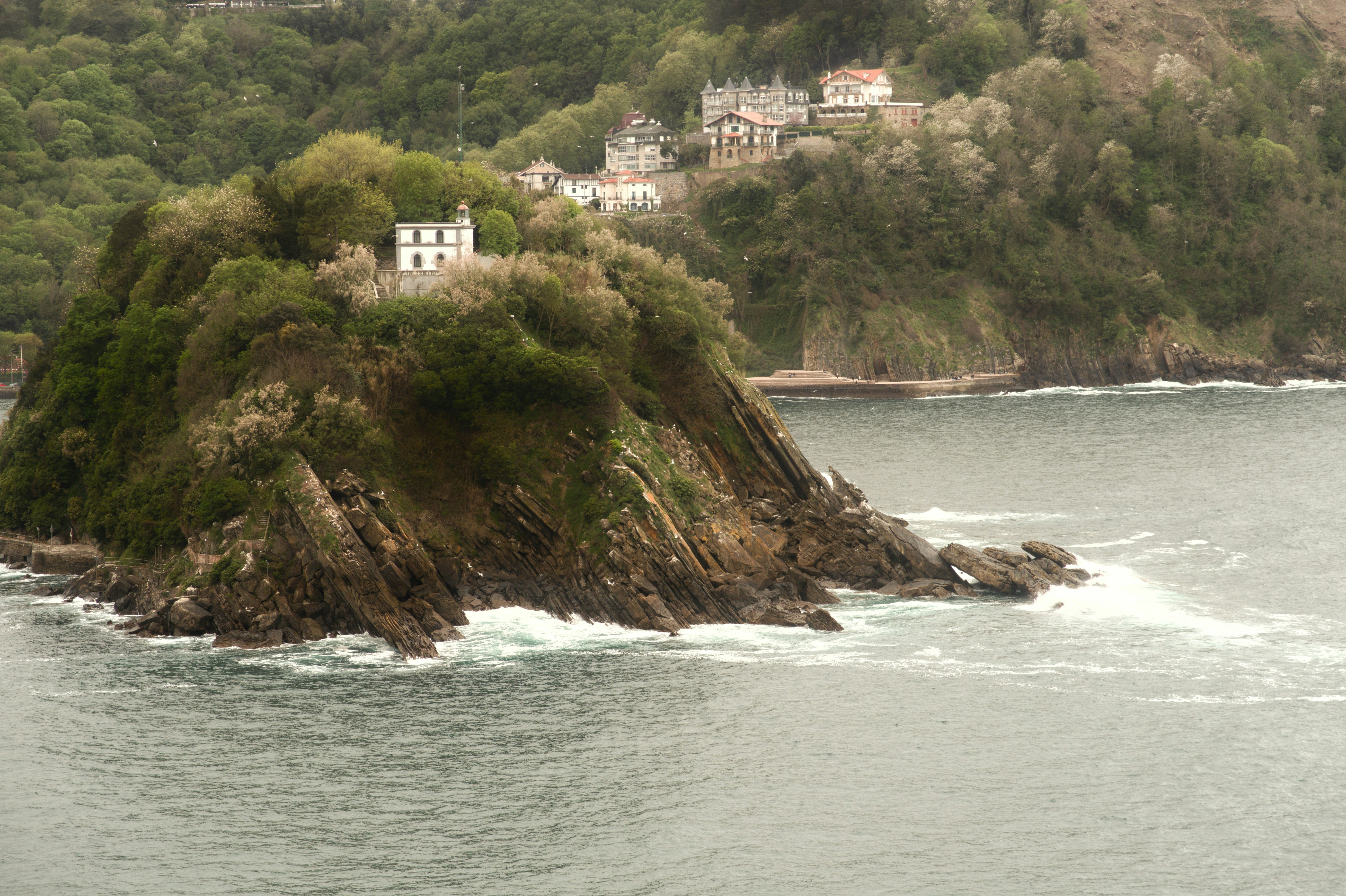 A small white house sits on a rocky island