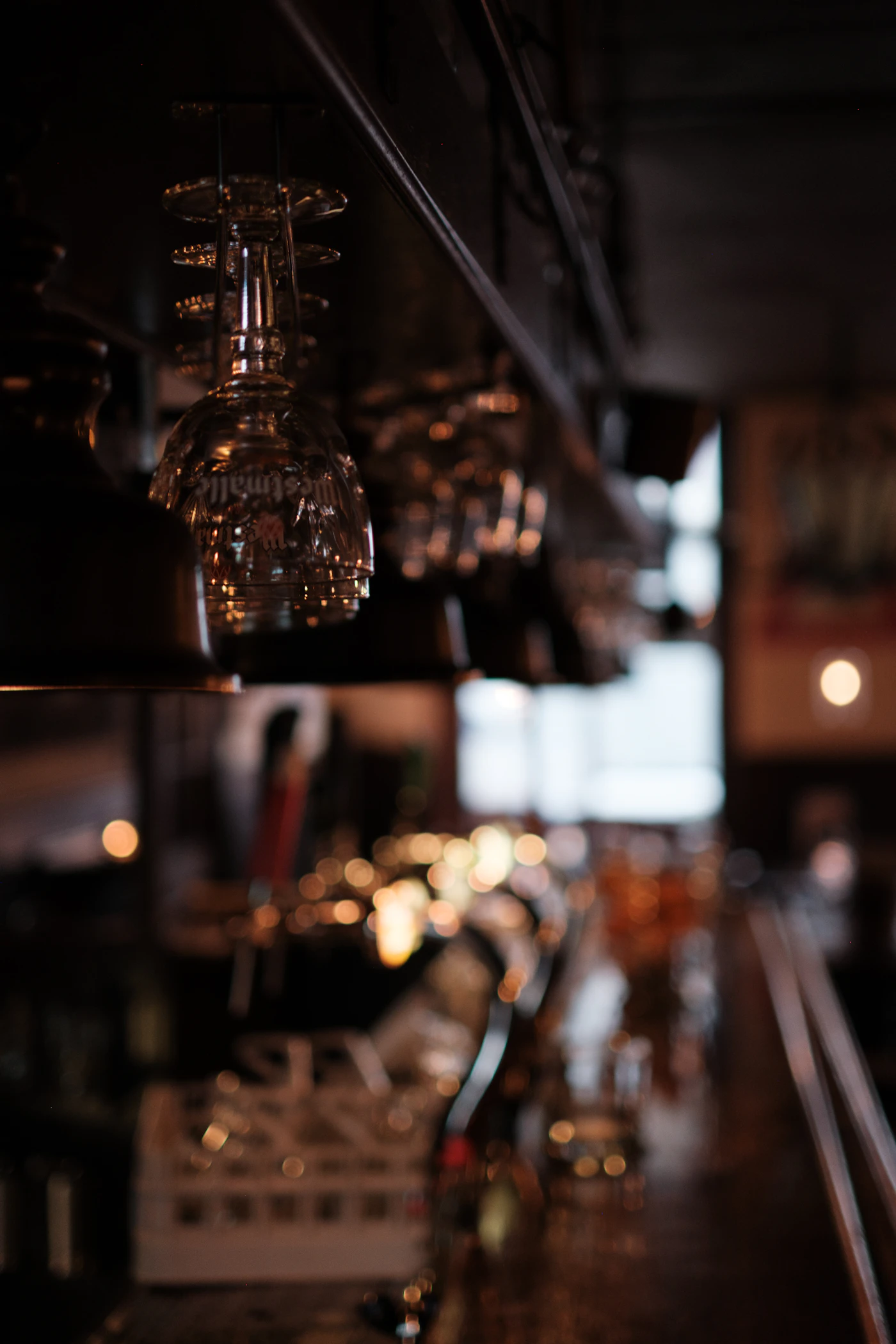 Empty wine glasses hanging above a bar counter