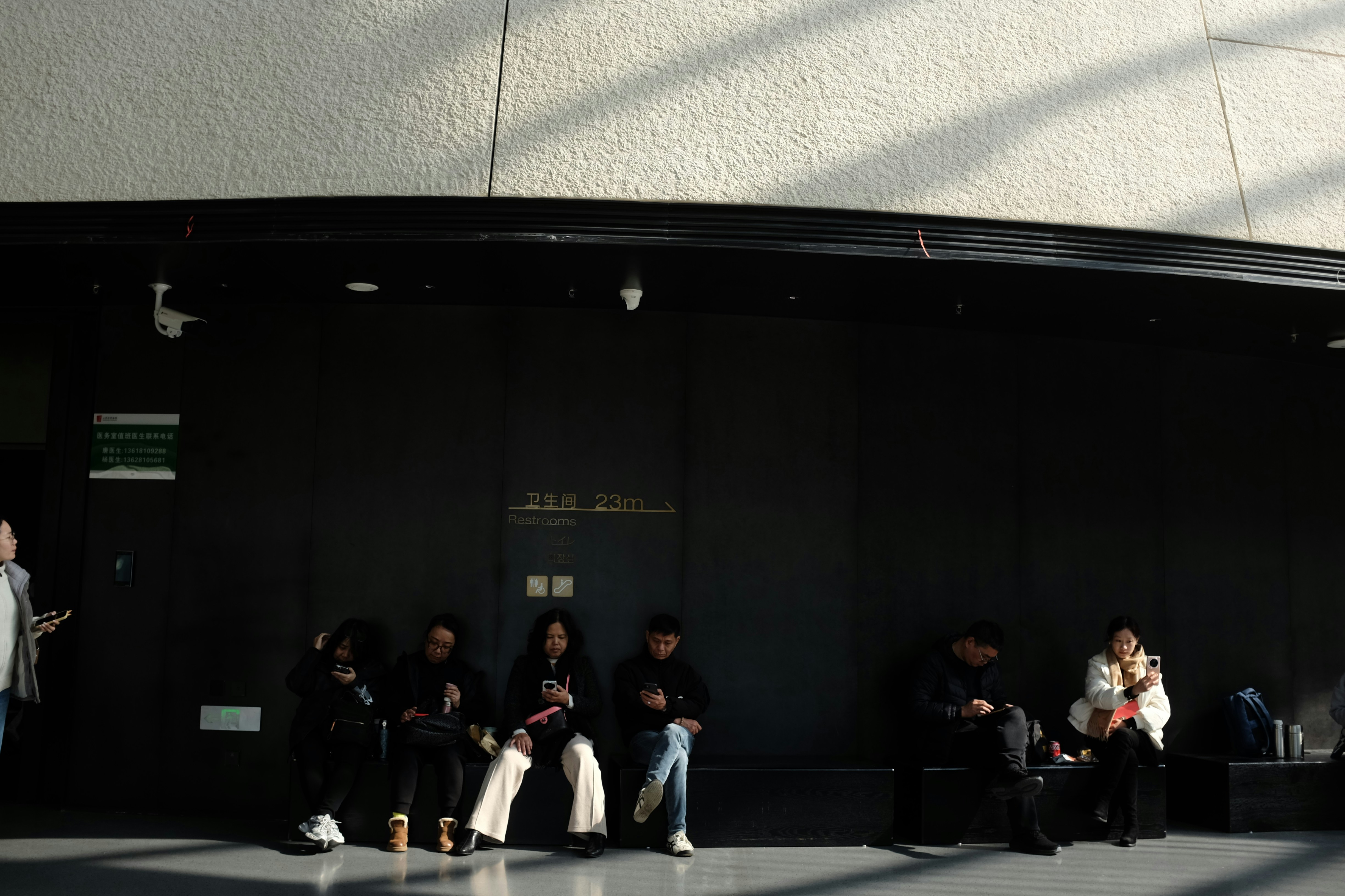 Menschen, die in einem dunklen Wartebereich mit Sonnenlicht sitzen
