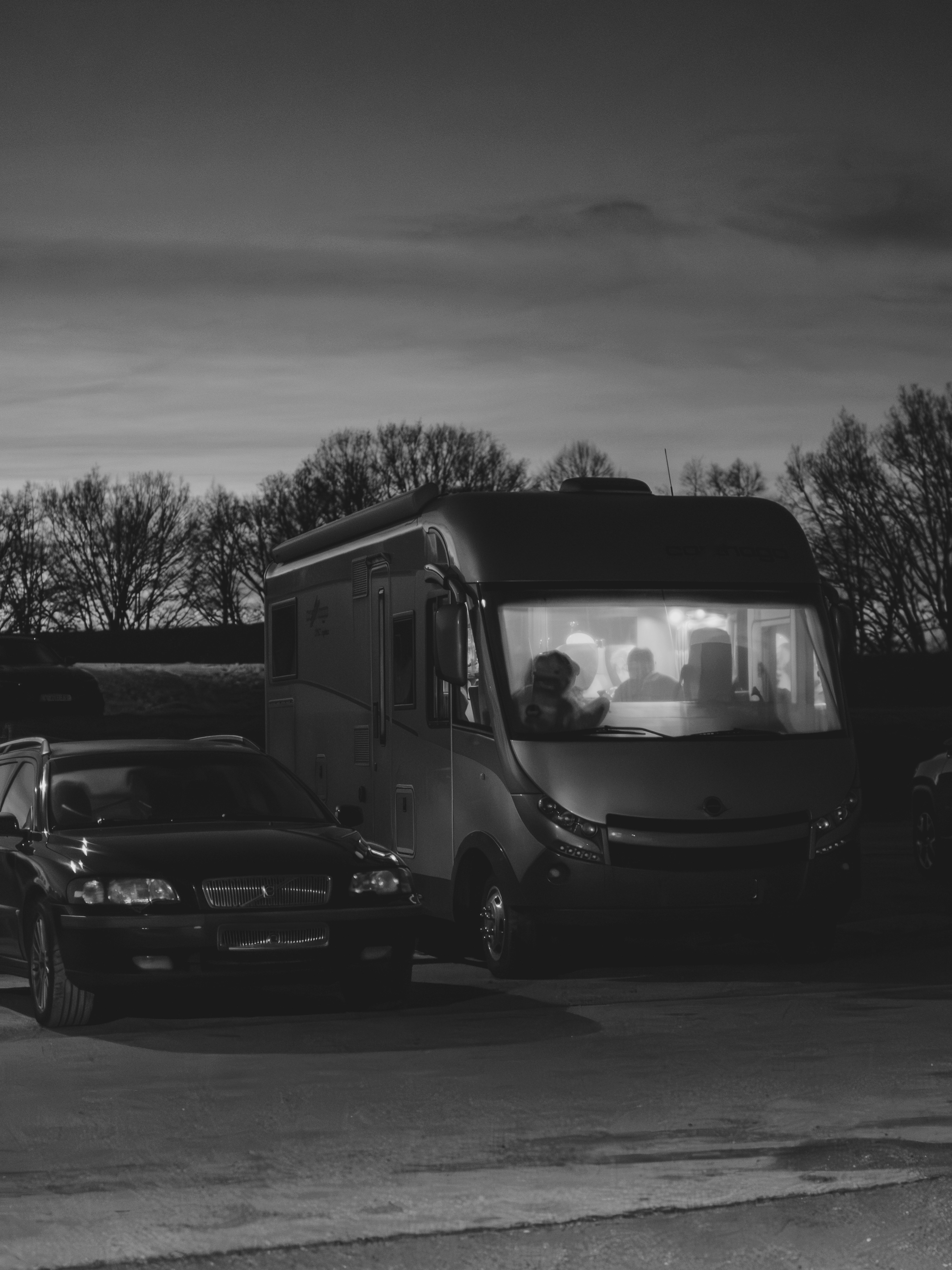 Una furgoneta camper y un coche aparcados al anochecer