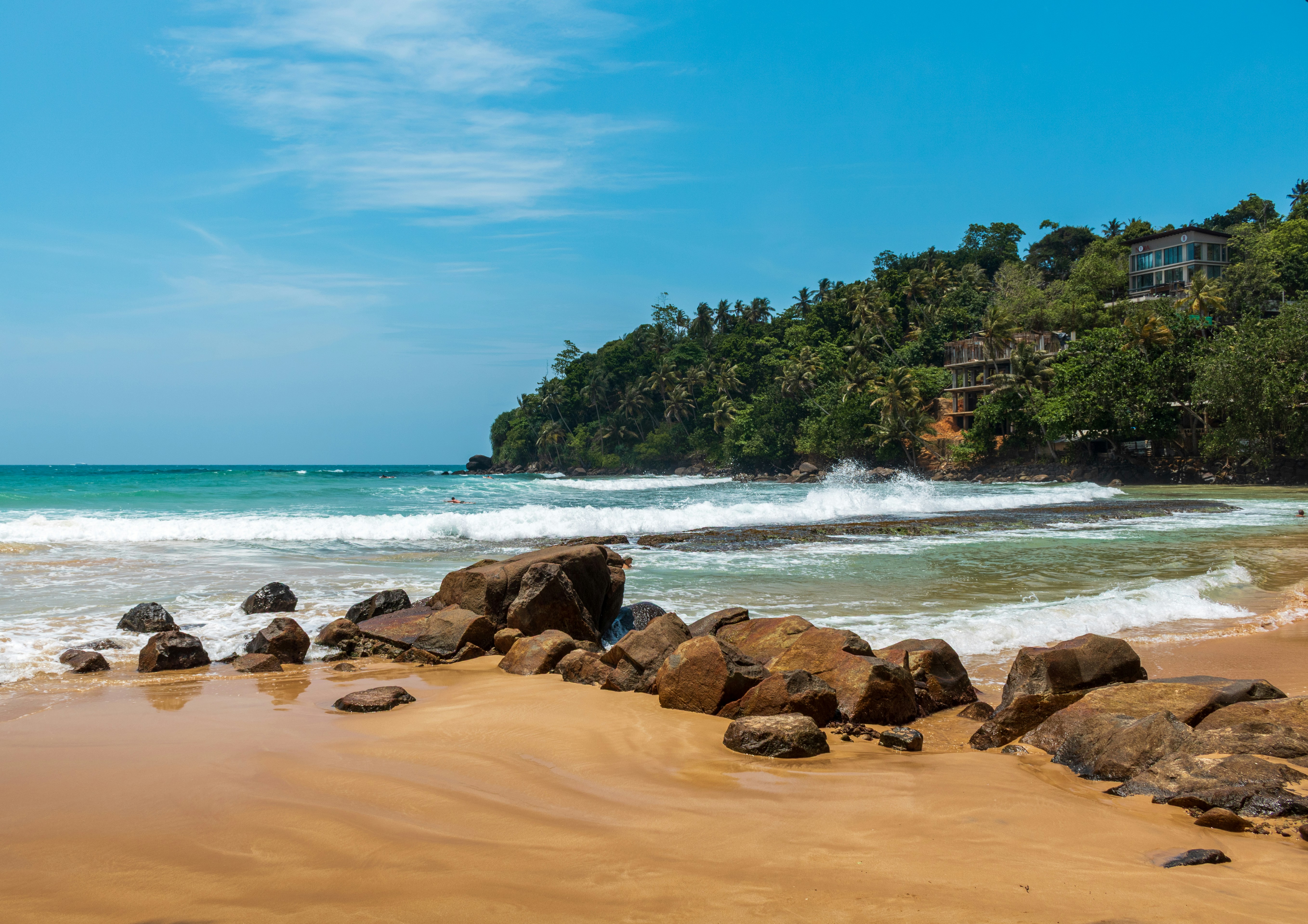 Waves crashing on a rocky beach with lush green hills.