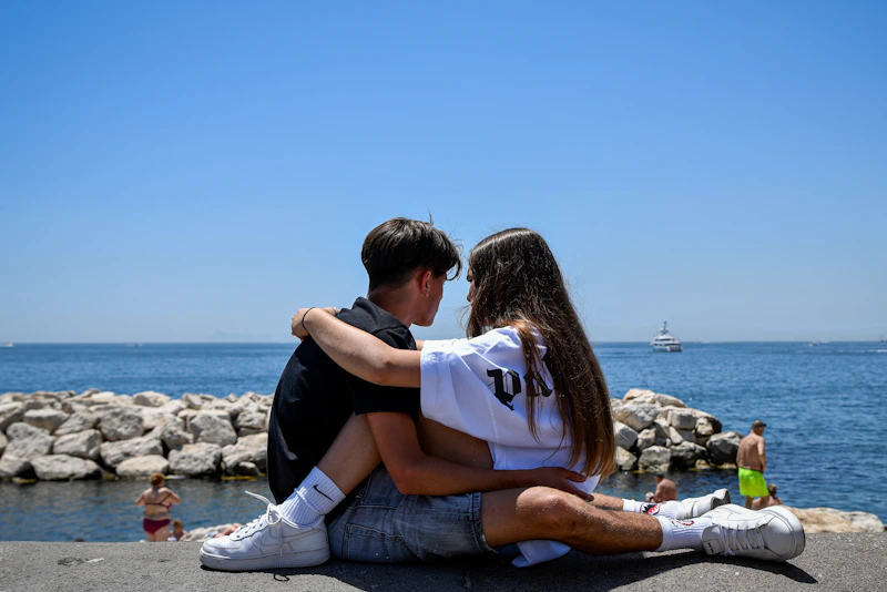 Couple sitting together by the ocean on a sunny day