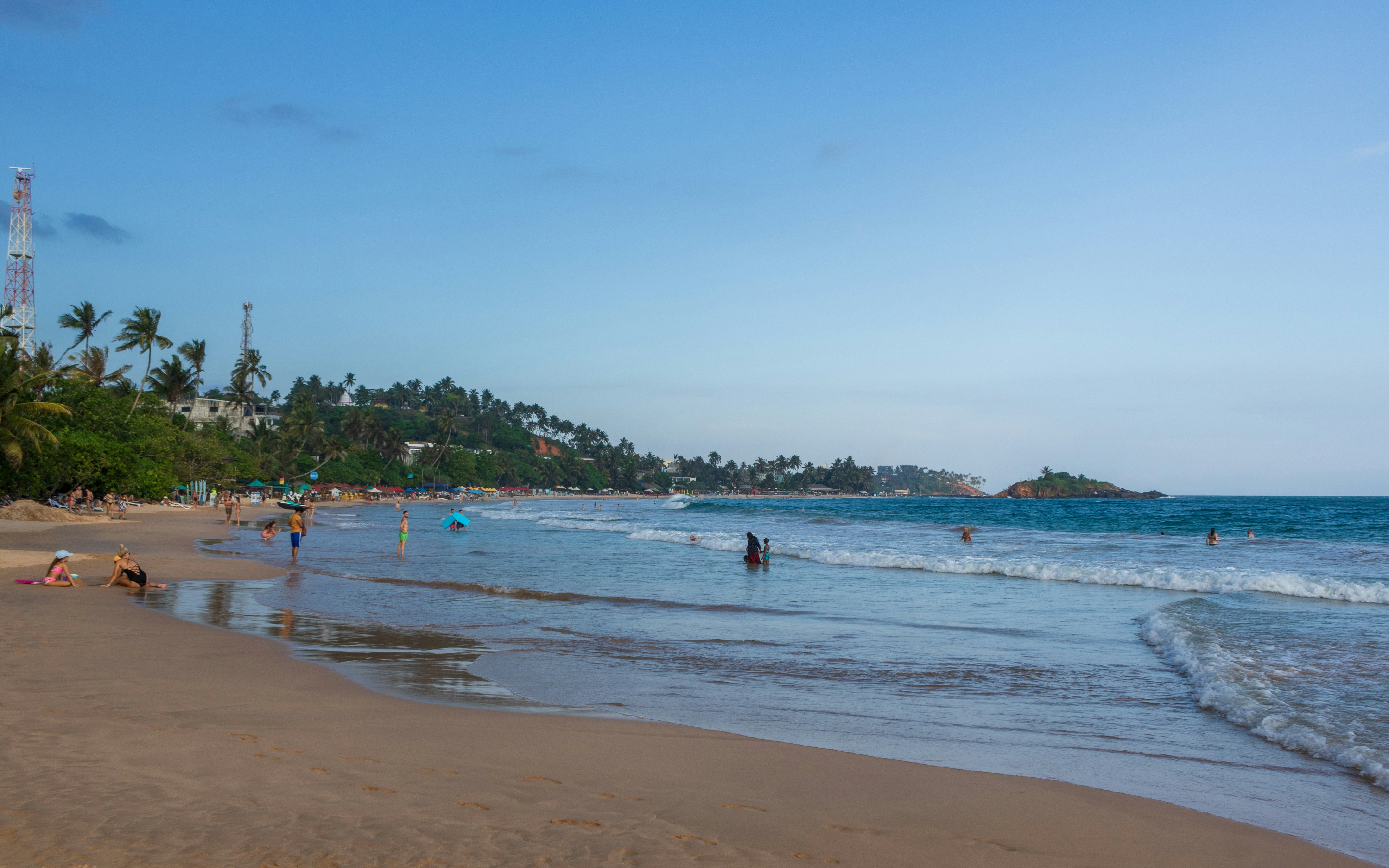 People enjoying a sunny day at a crowded tropical beach.