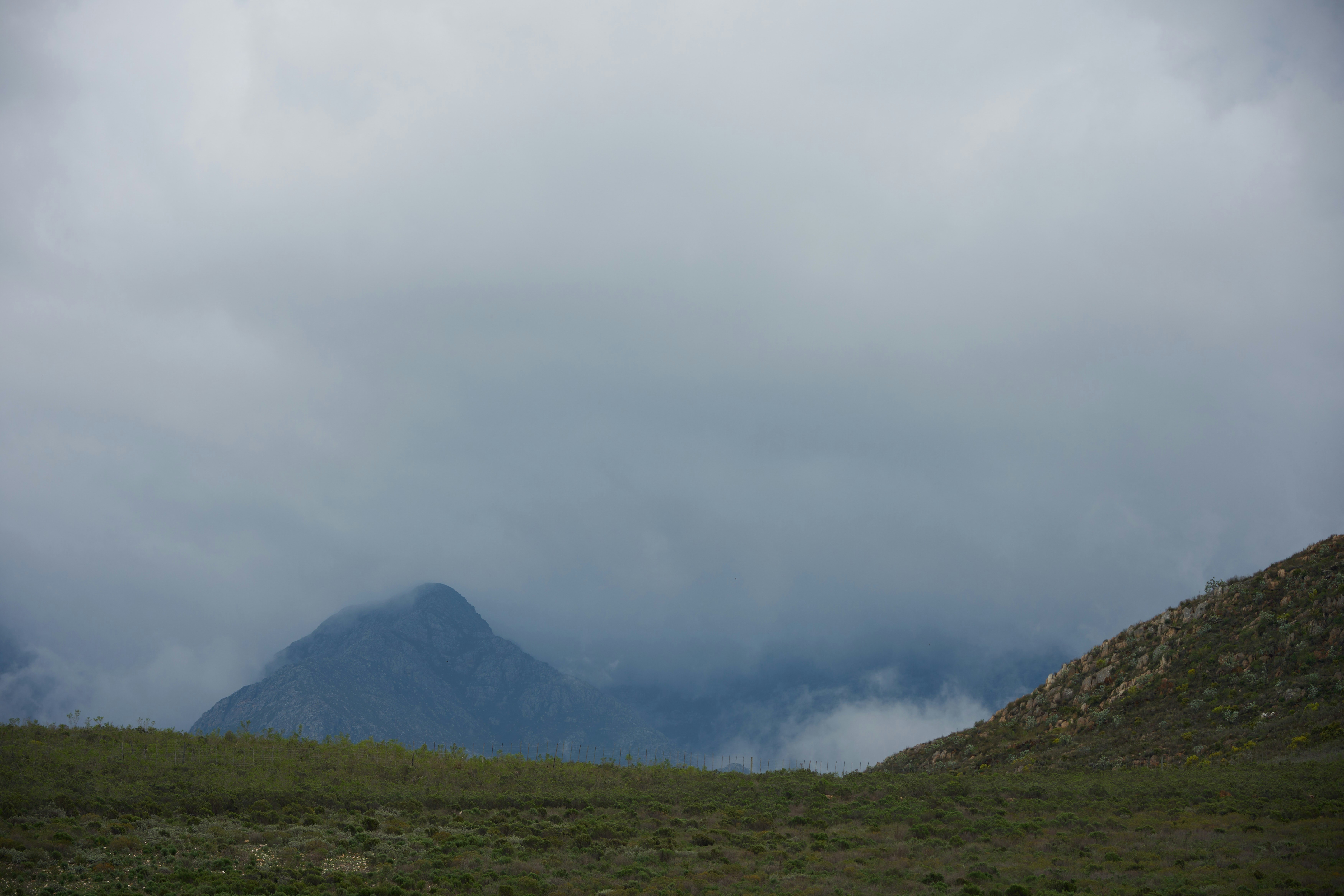 Misty mountains shrouded in clouds over grassy hills.