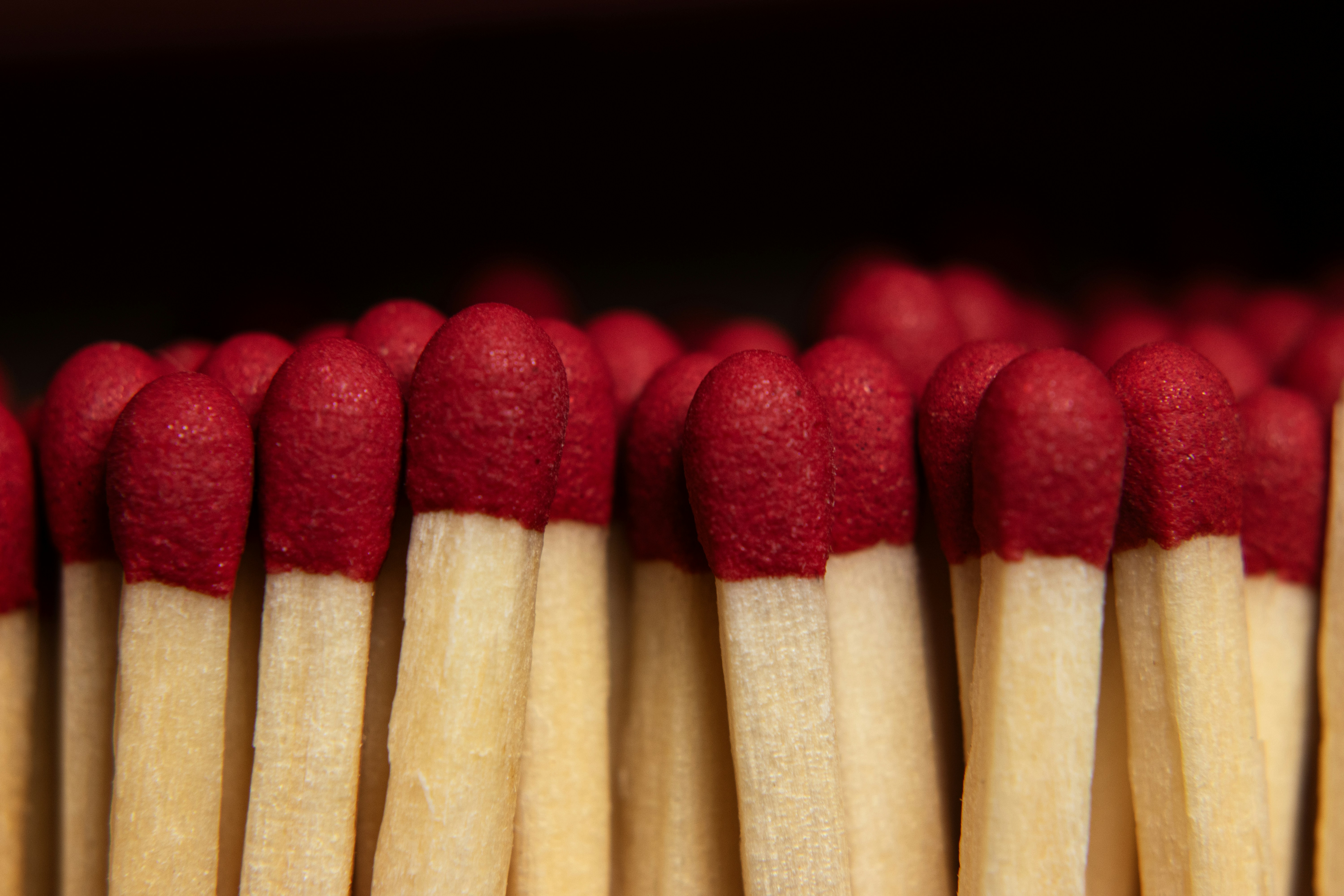 A close-up of many red-tipped matches against a dark background