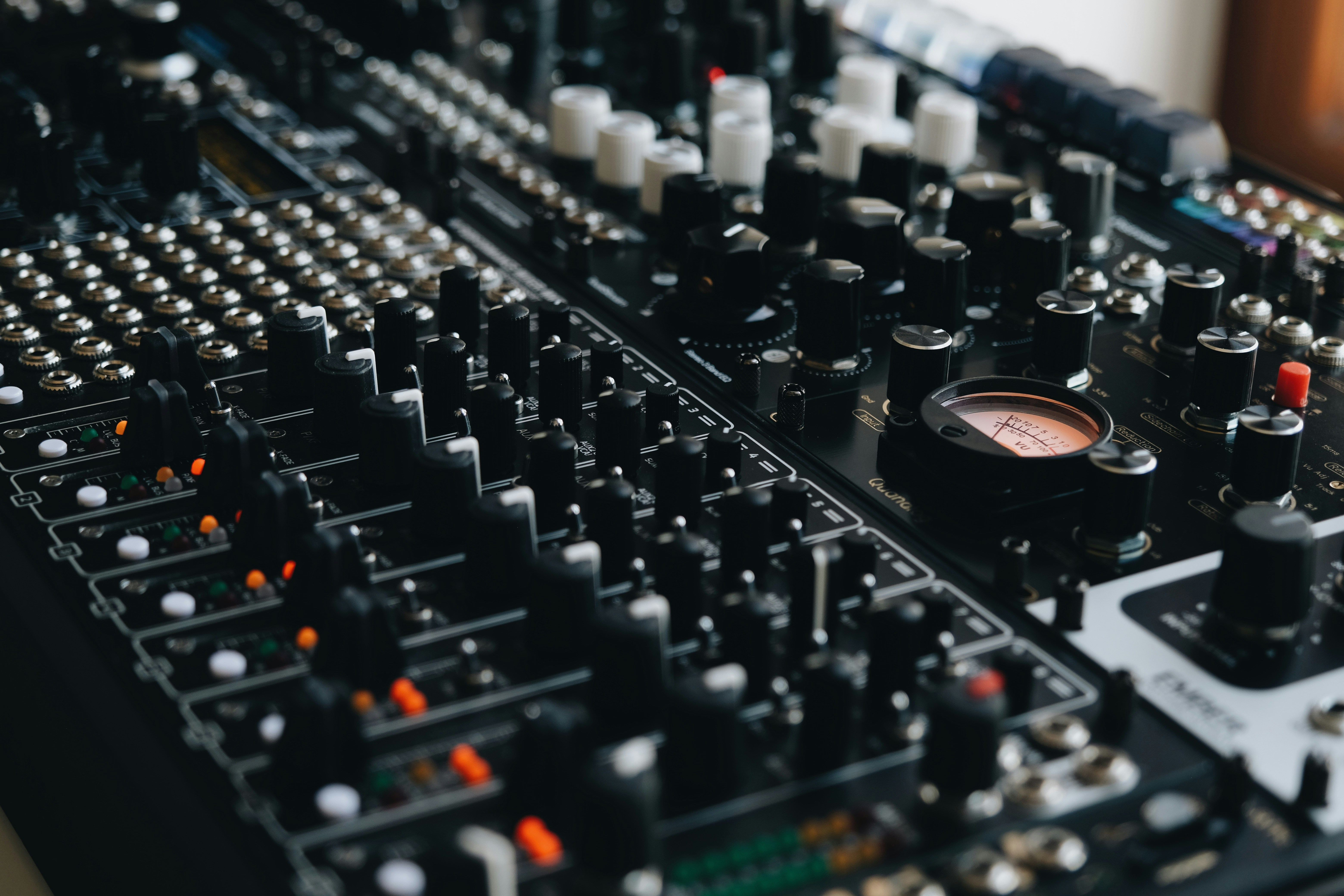 Close-up of a complex audio mixing board with many knobs.