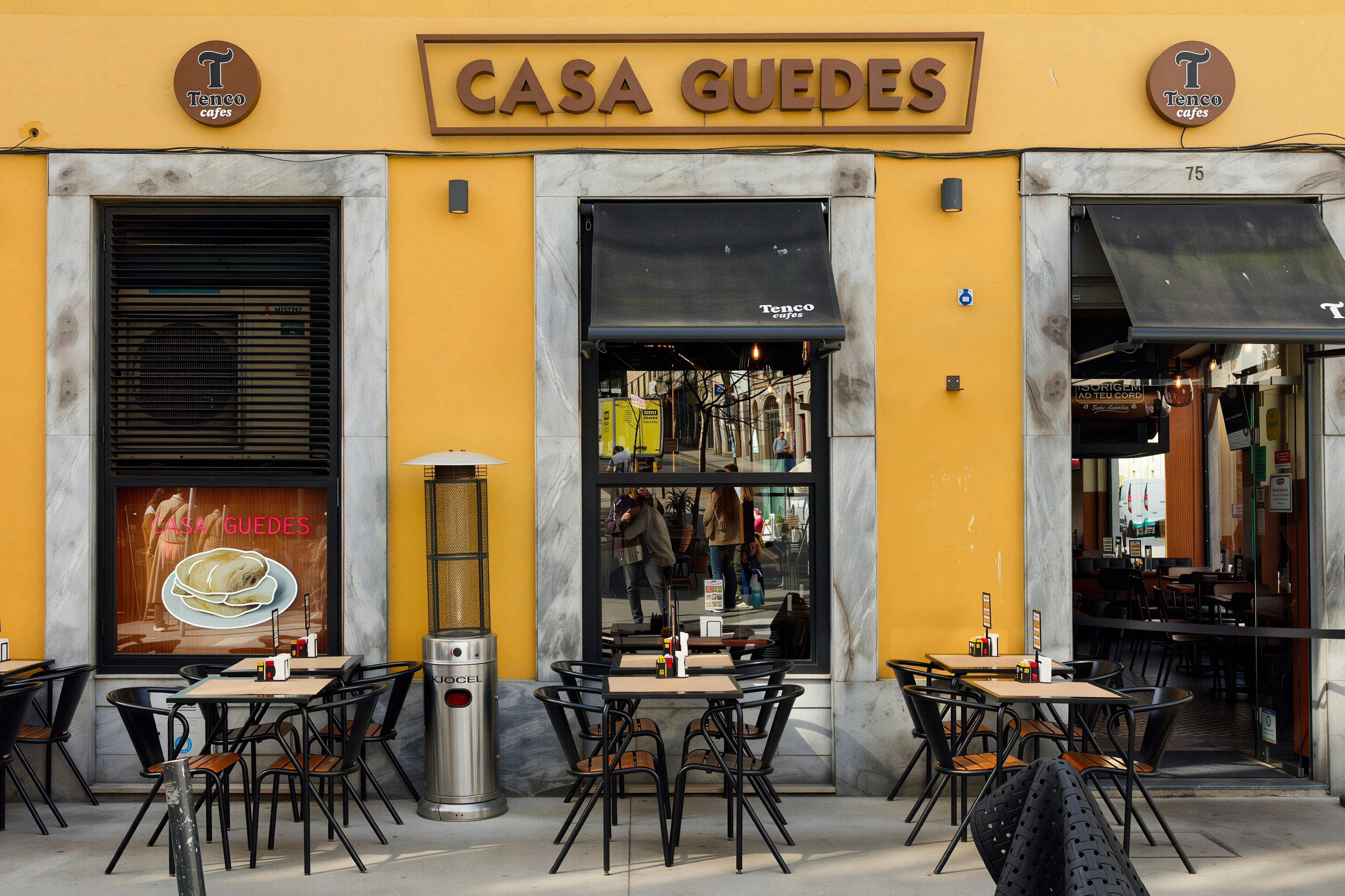 Visitors gather outside Casa Guedes restaurant in Porto, Portugal during midday for food and drinks under clear skies - Casa Guedes in Porto shows empty tables waiting for guests to enjoy food and drinks. The sun shines down on the outdoor seating area where people will soon arrive.