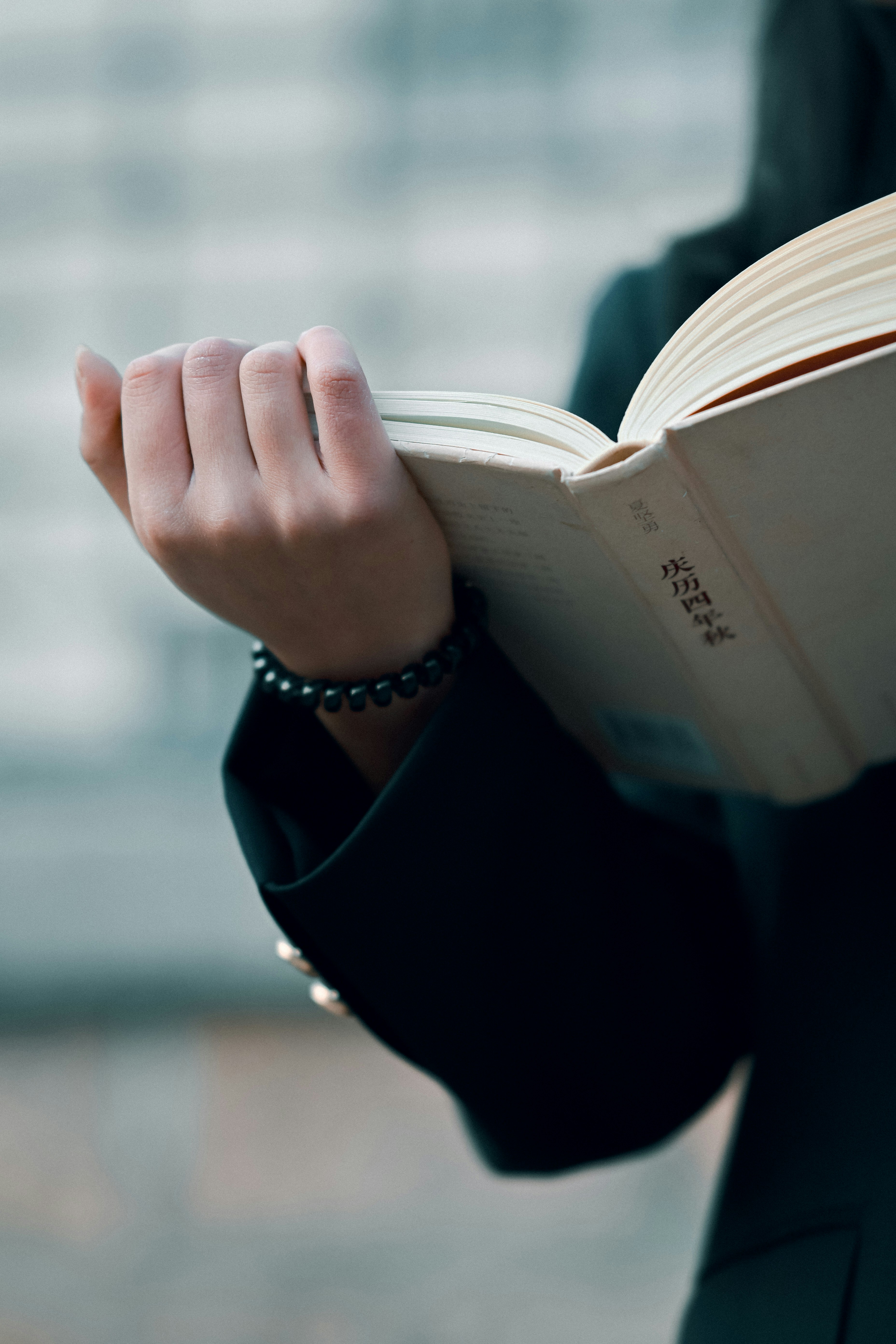 Person reading an open book with a bracelet.