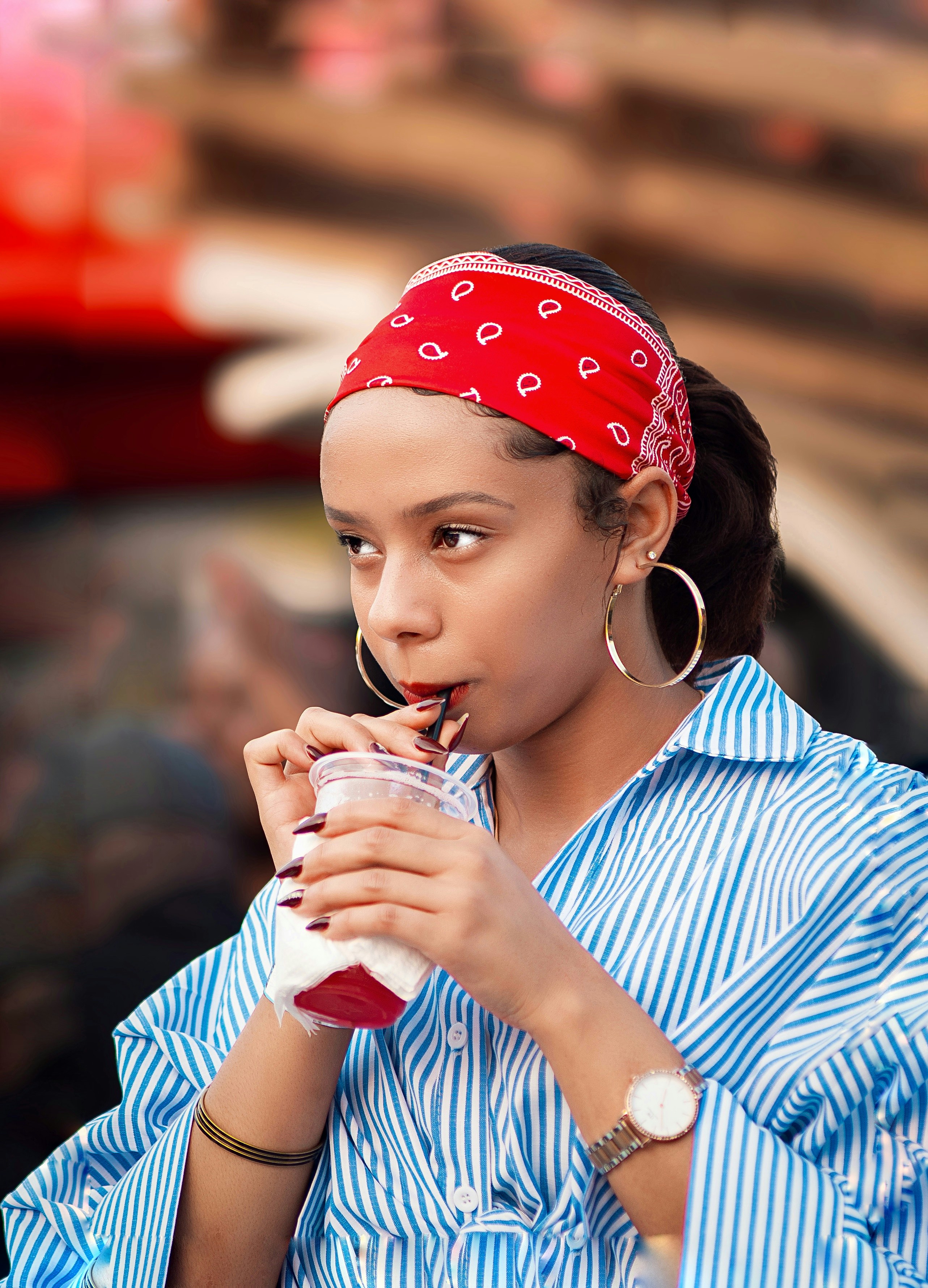 Young woman with bandana drinks from cup