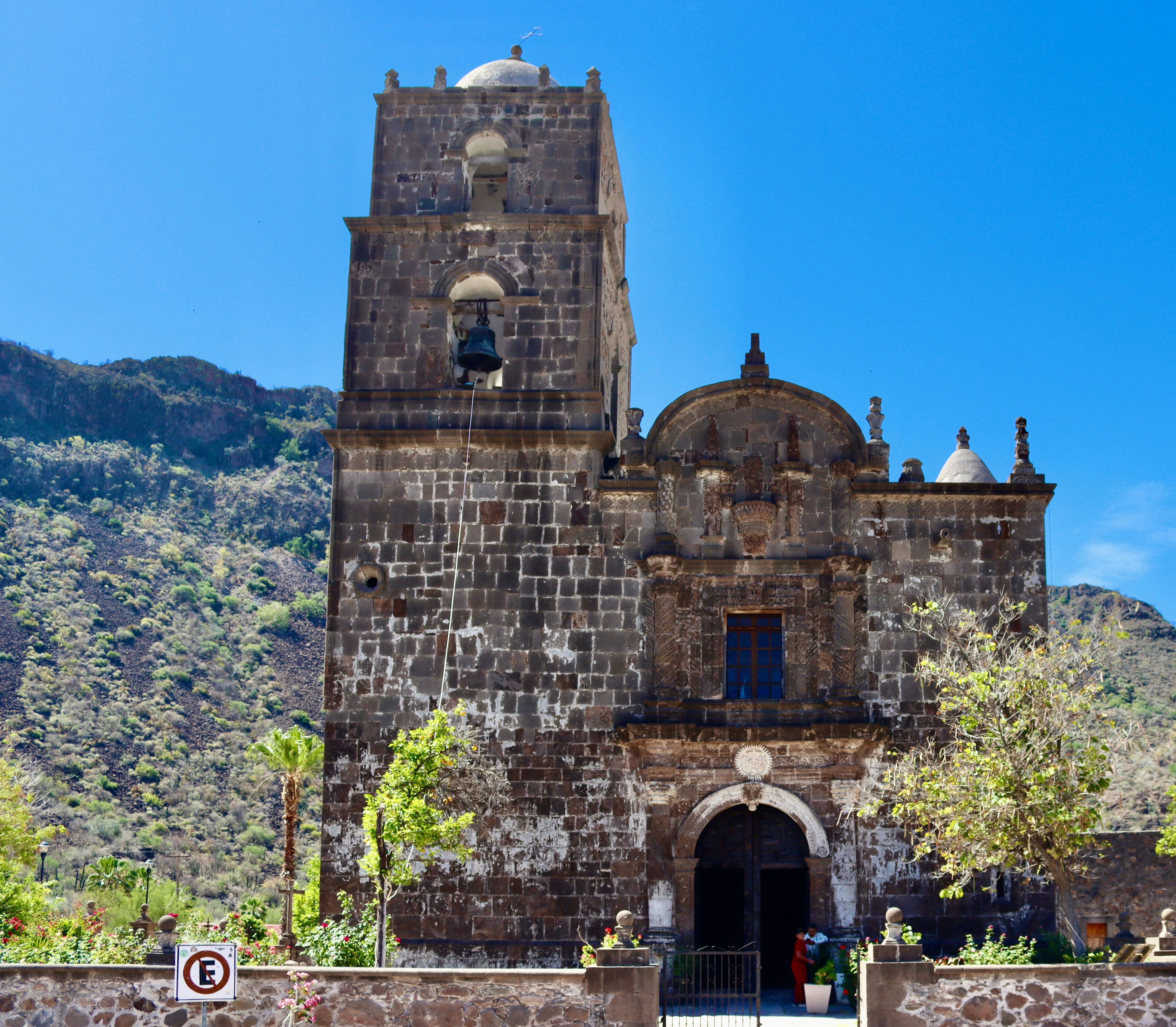 Historic stone church with a bell tower under blue sky.