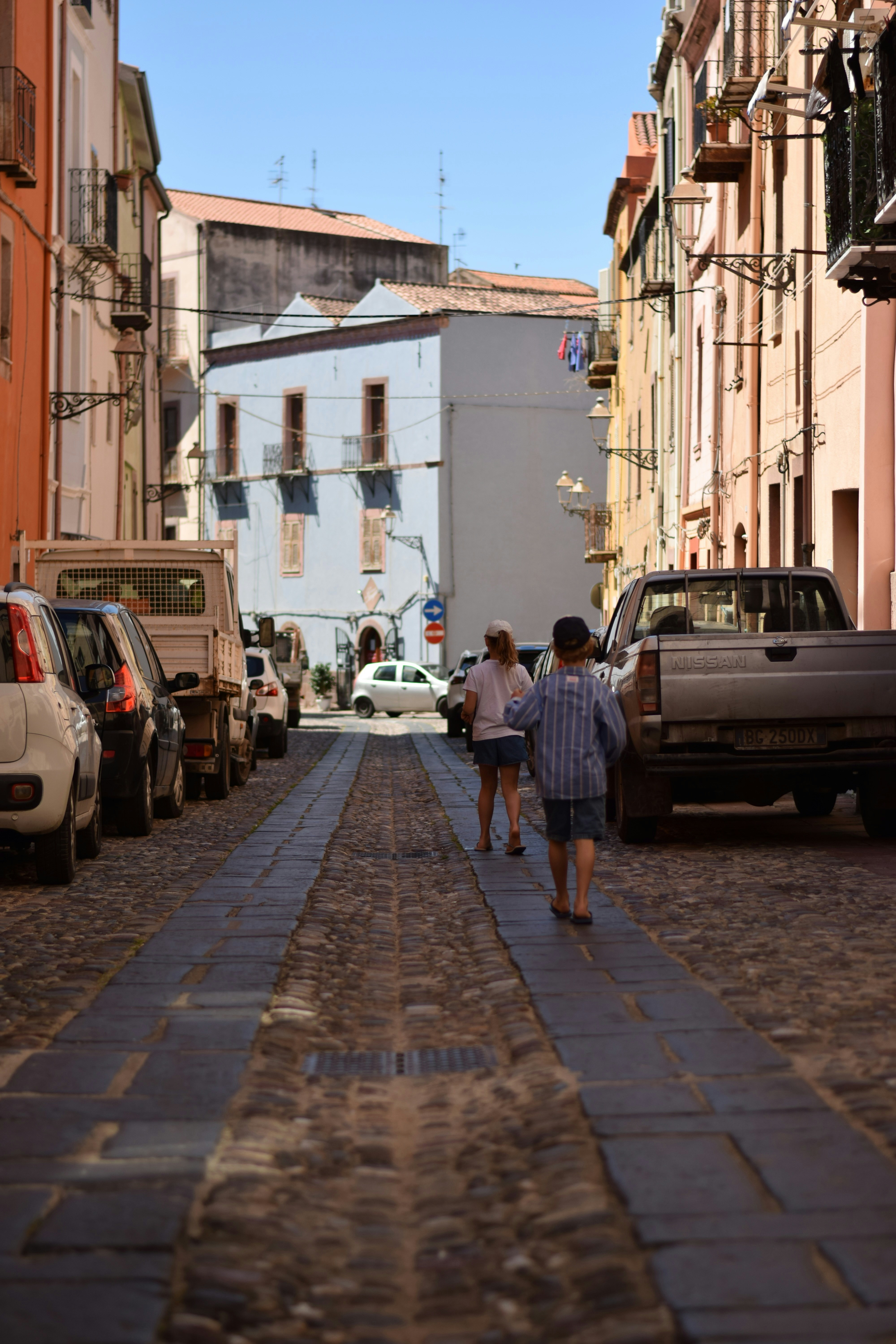 Due bambini camminano lungo una strada di ciottoli.