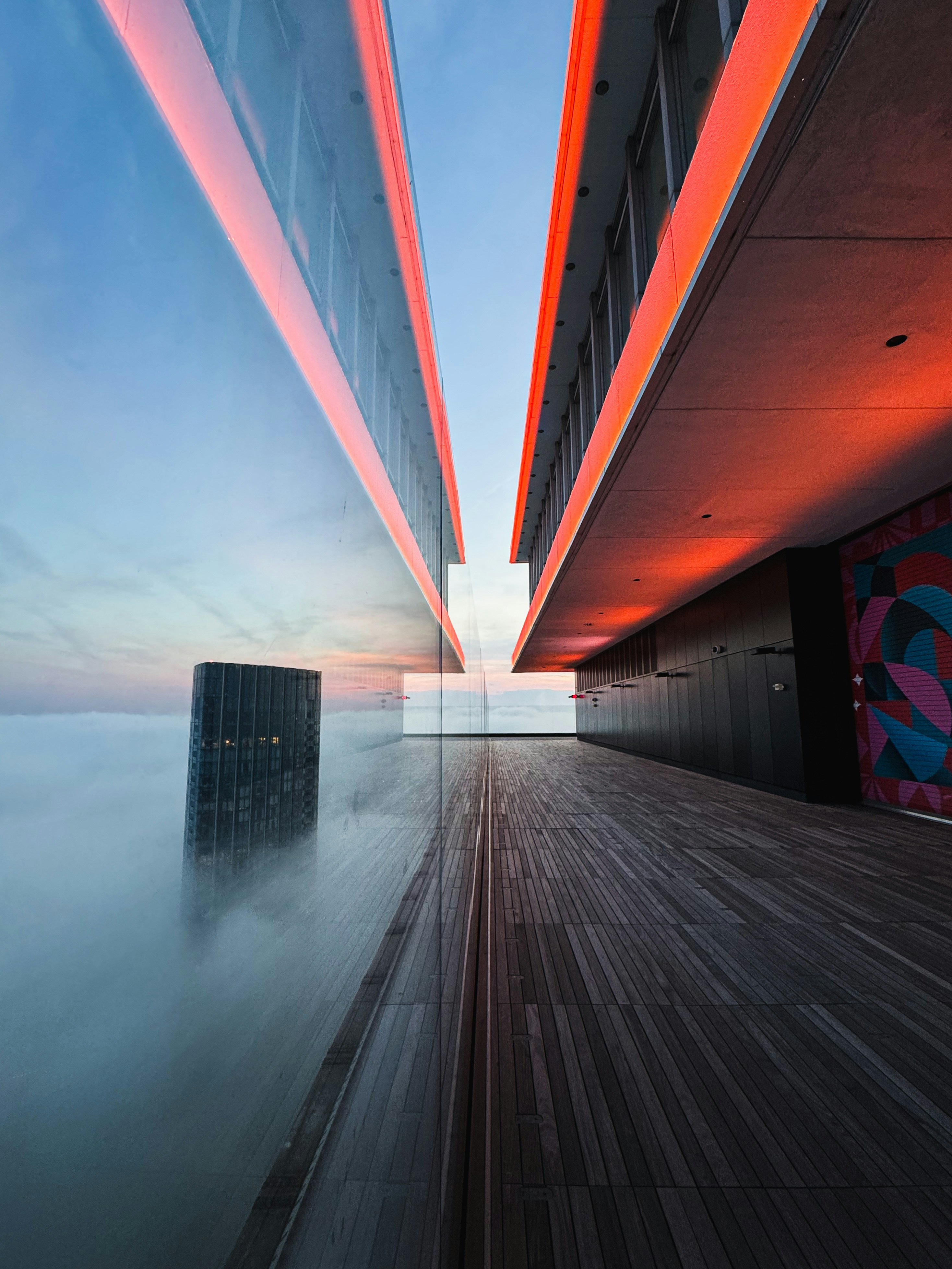 Edificio moderno con luces naranjas sobre la ciudad brumosa