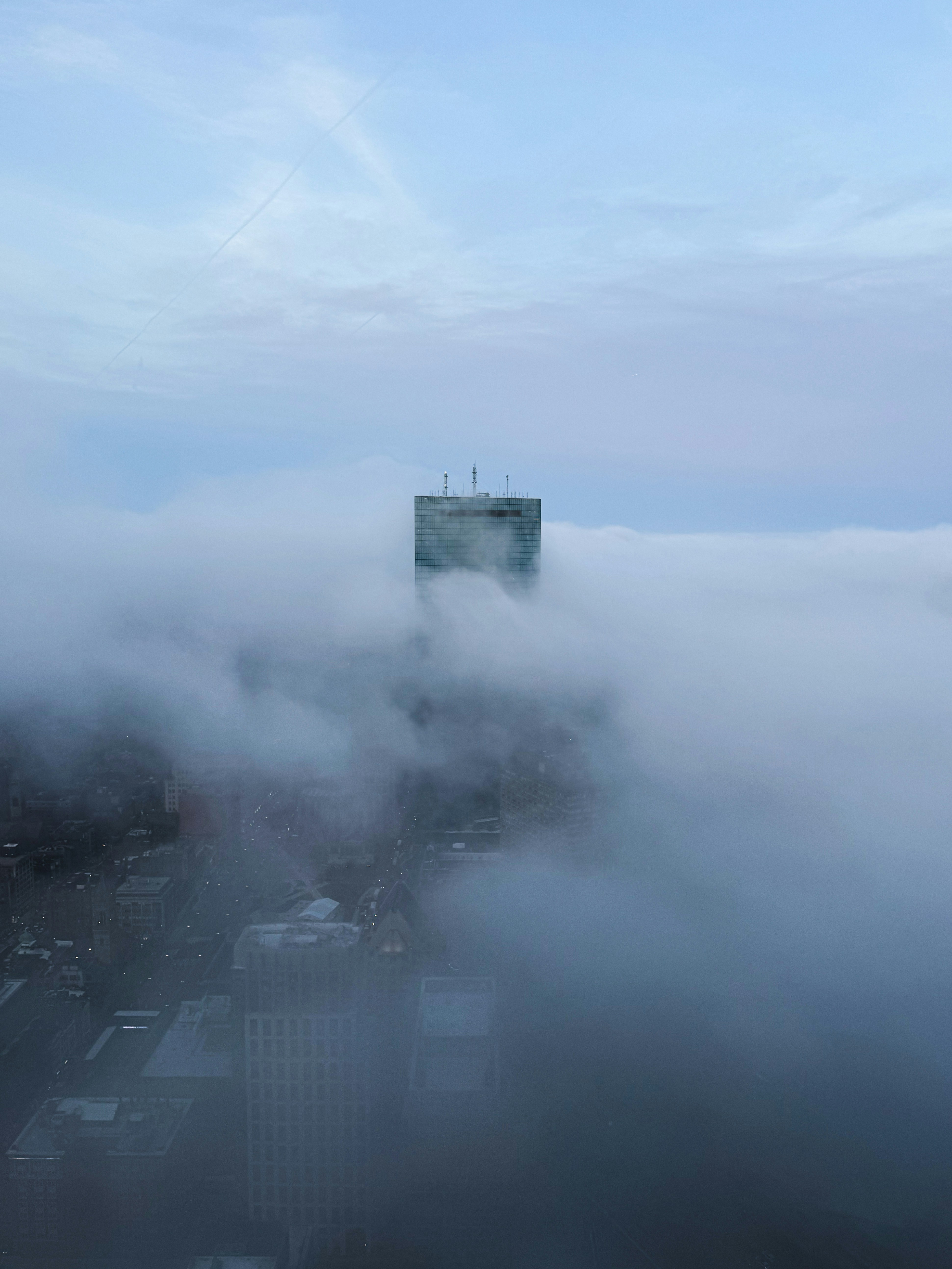 Un rascacielos emerge de una densa niebla sobre la ciudad