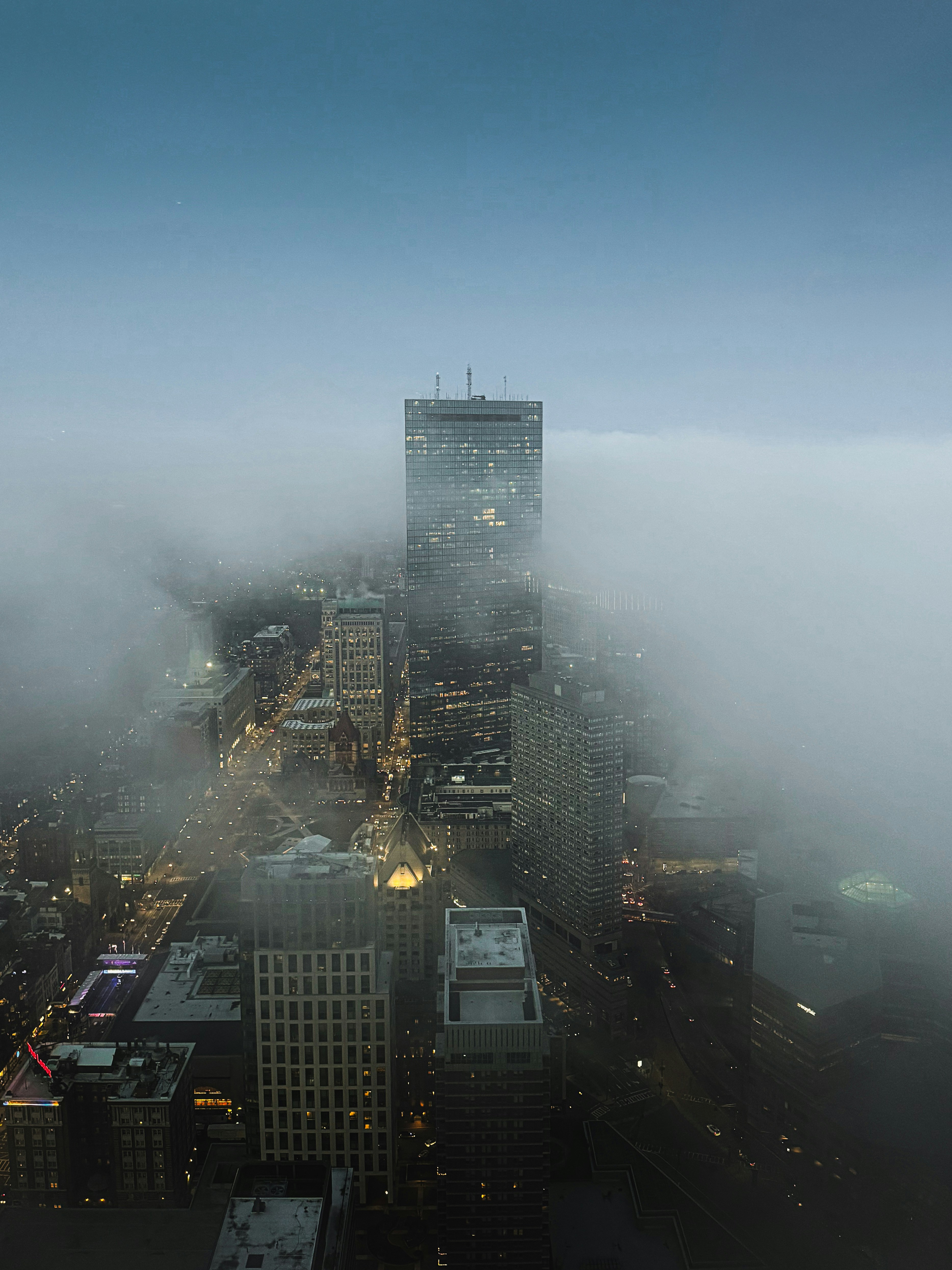 Paisaje urbano con niebla con rascacielos iluminados al anochecer
