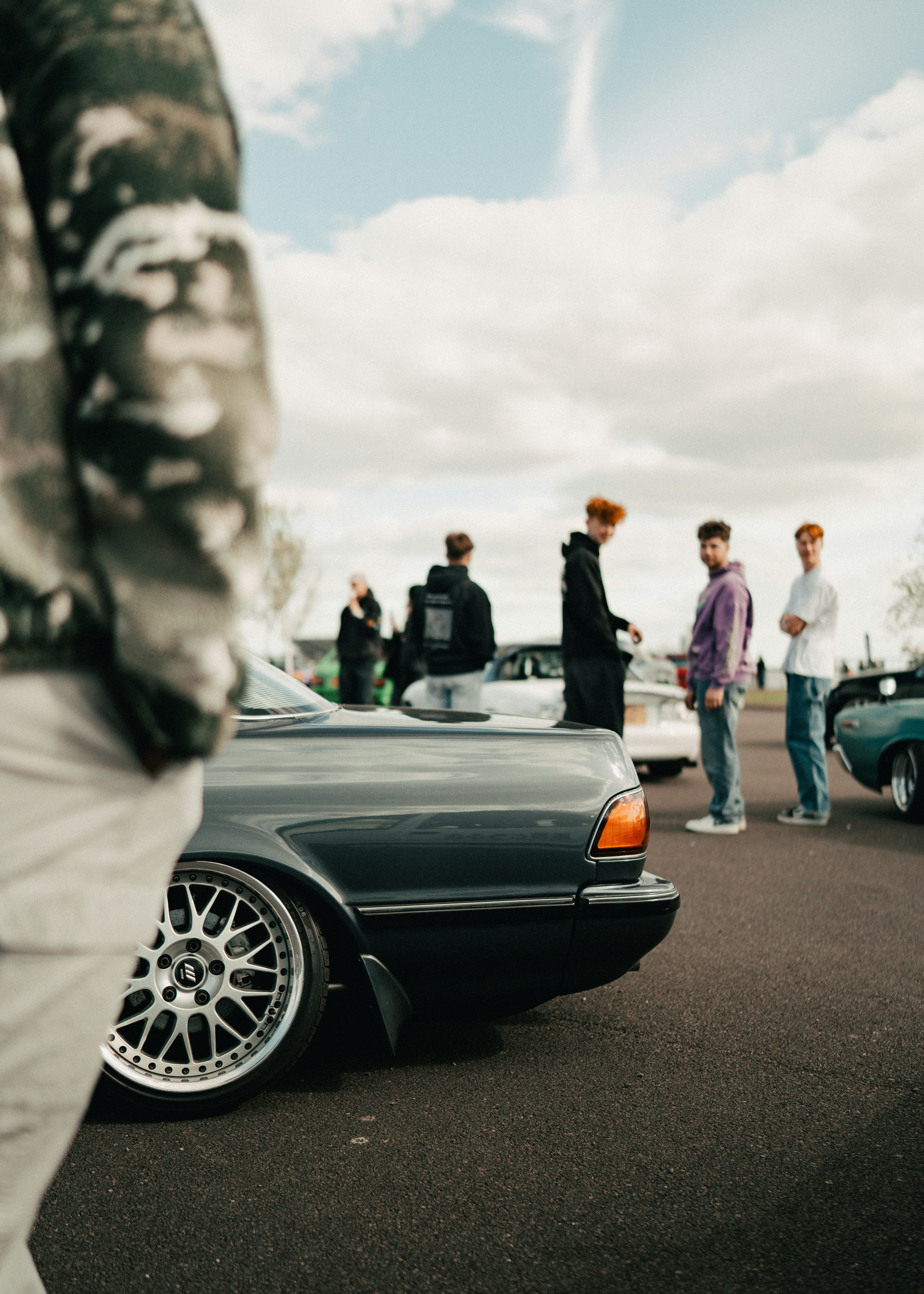 People gathered around classic cars at an outdoor event.