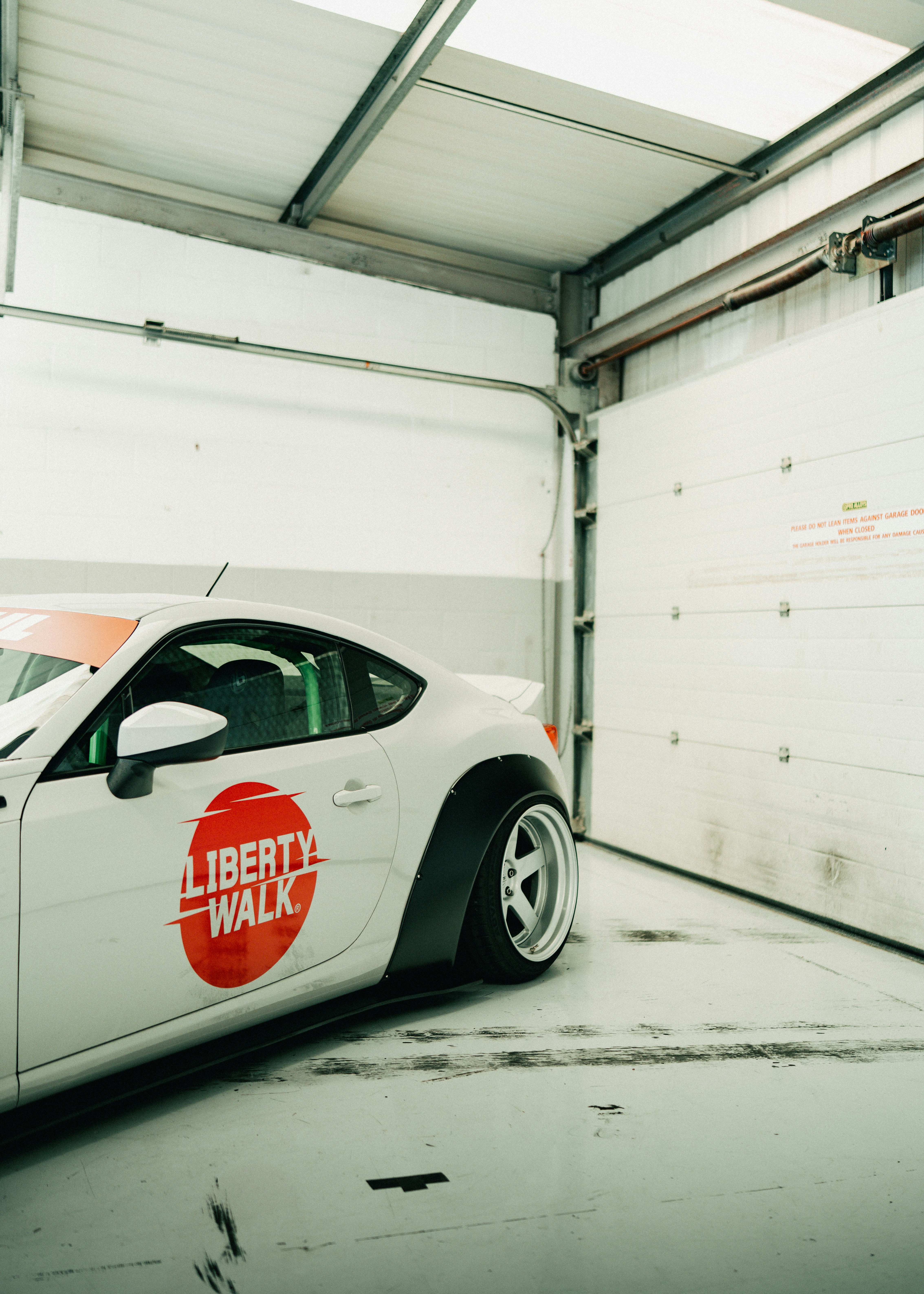 White sports car with liberty walk decal in garage