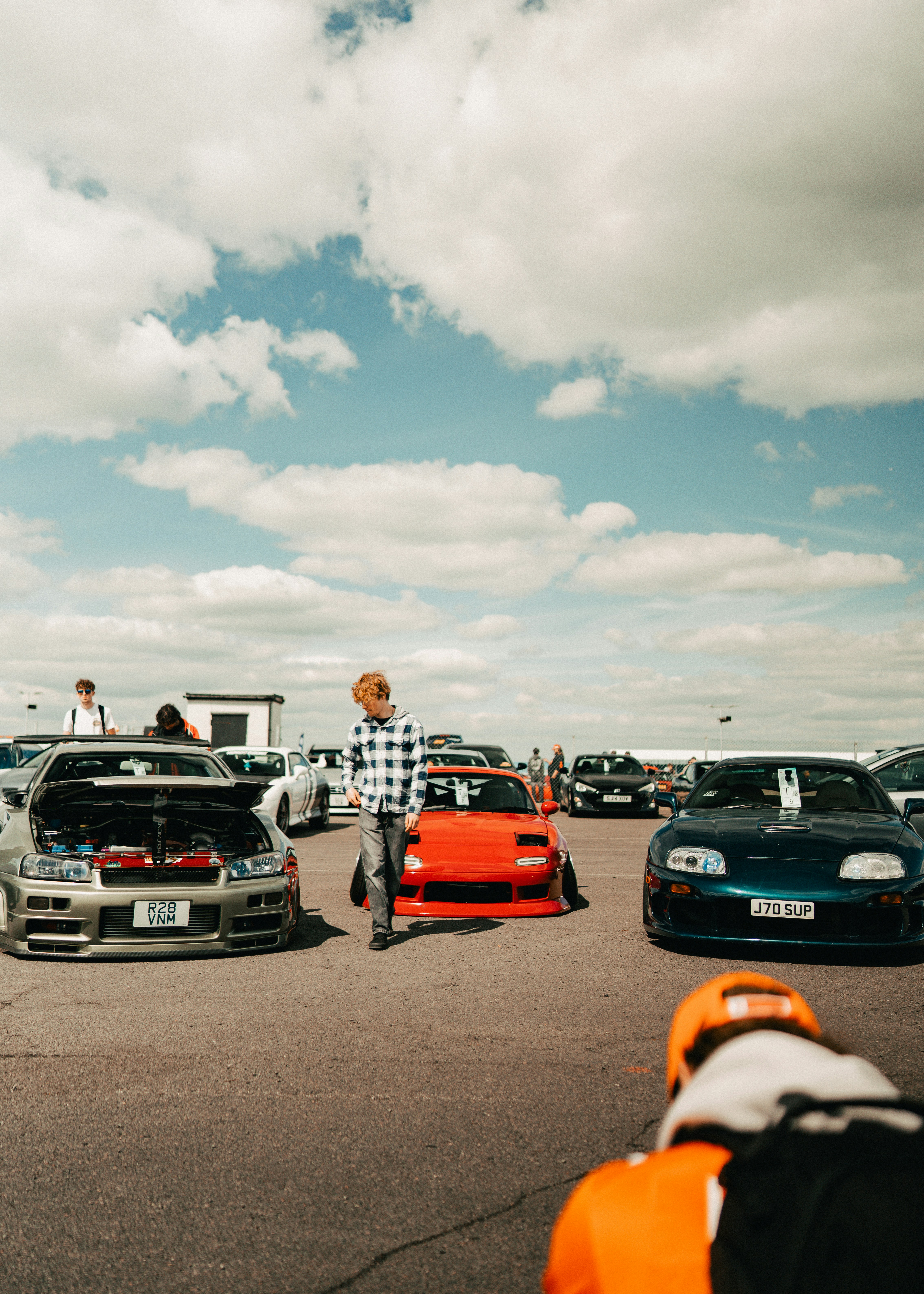 Cars gathered at an outdoor event under a cloudy sky.