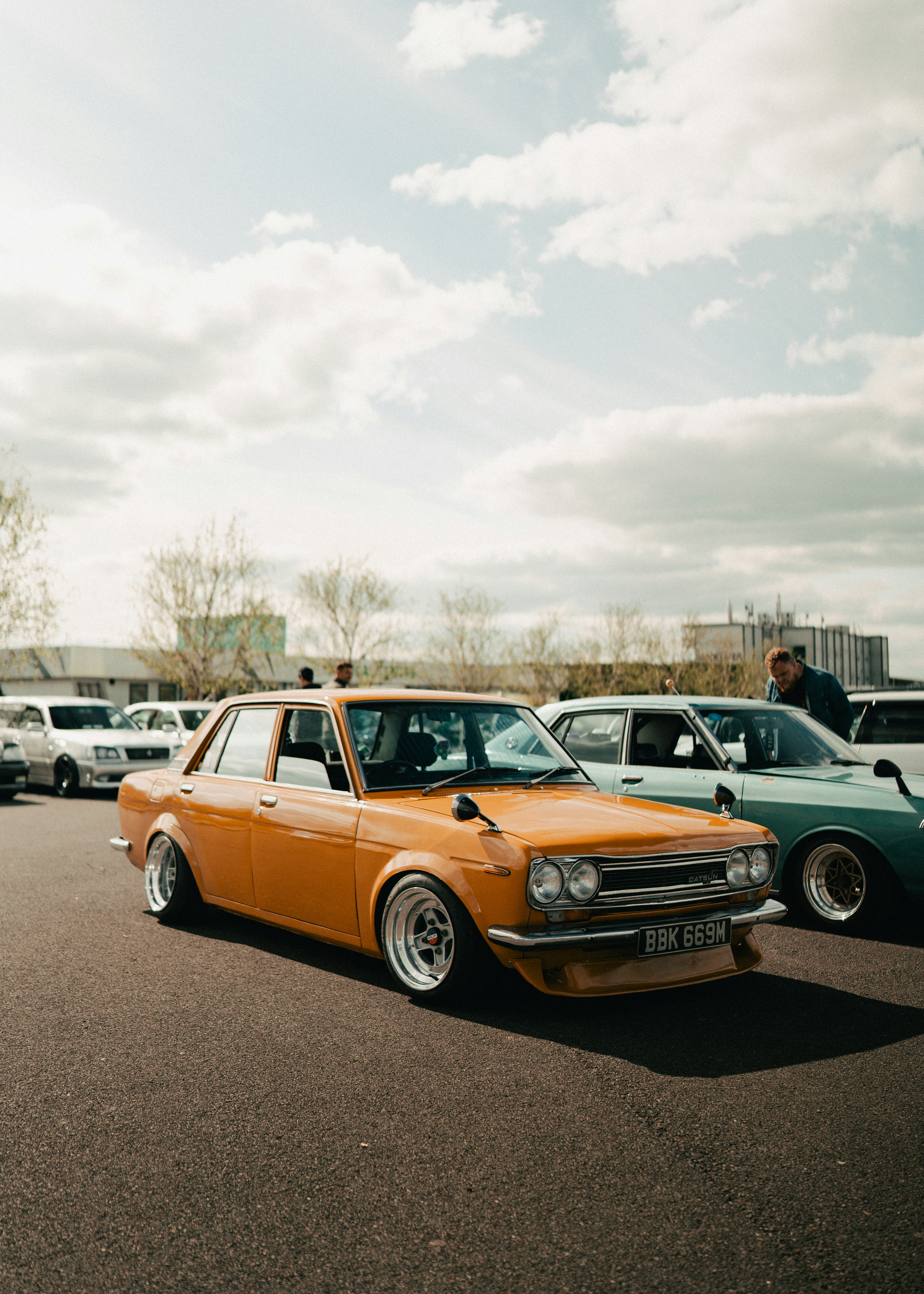 Orange vintage car parked outdoors under a cloudy sky