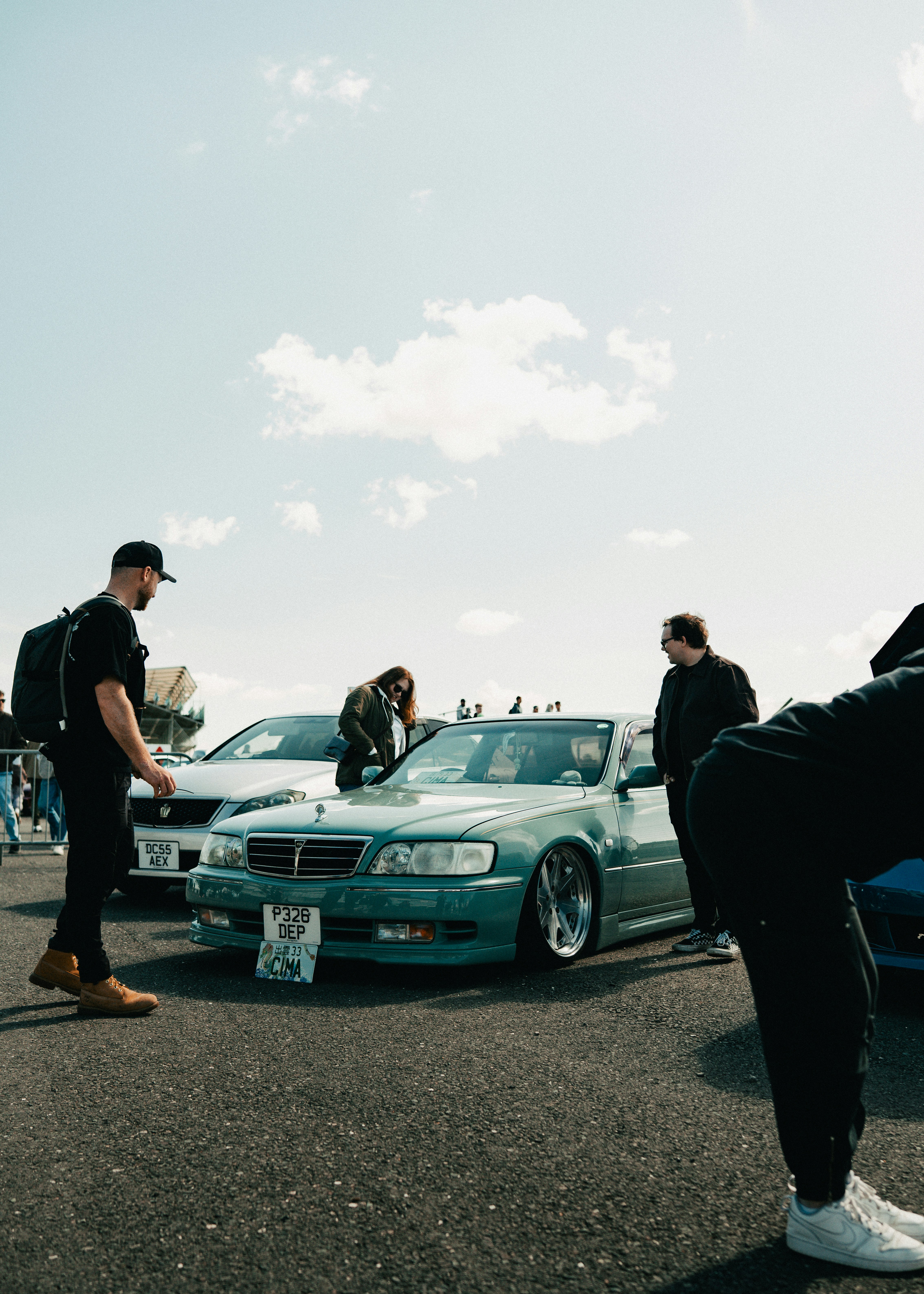 People gathered around custom cars at an outdoor event