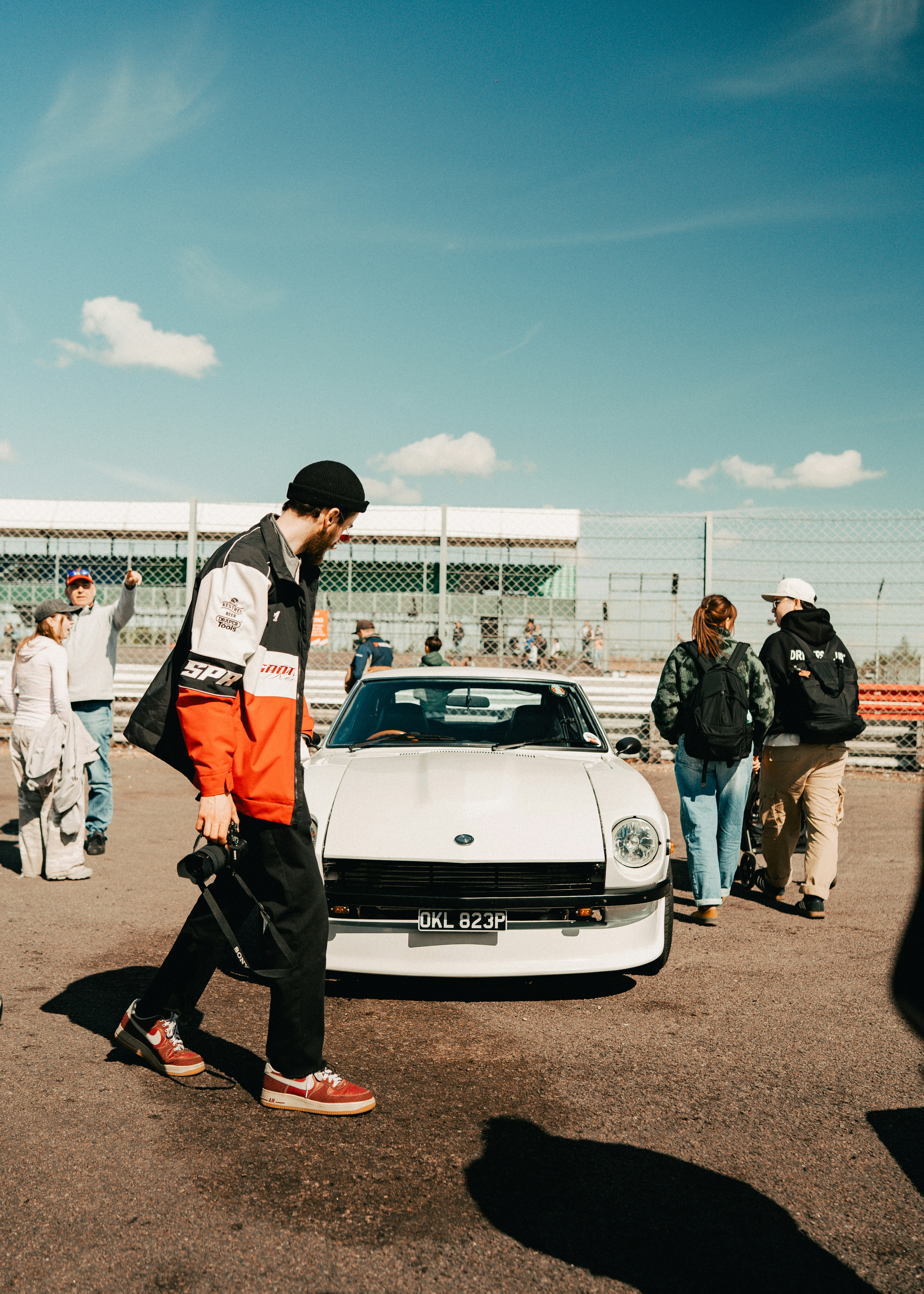 People gather around a white classic car outdoors