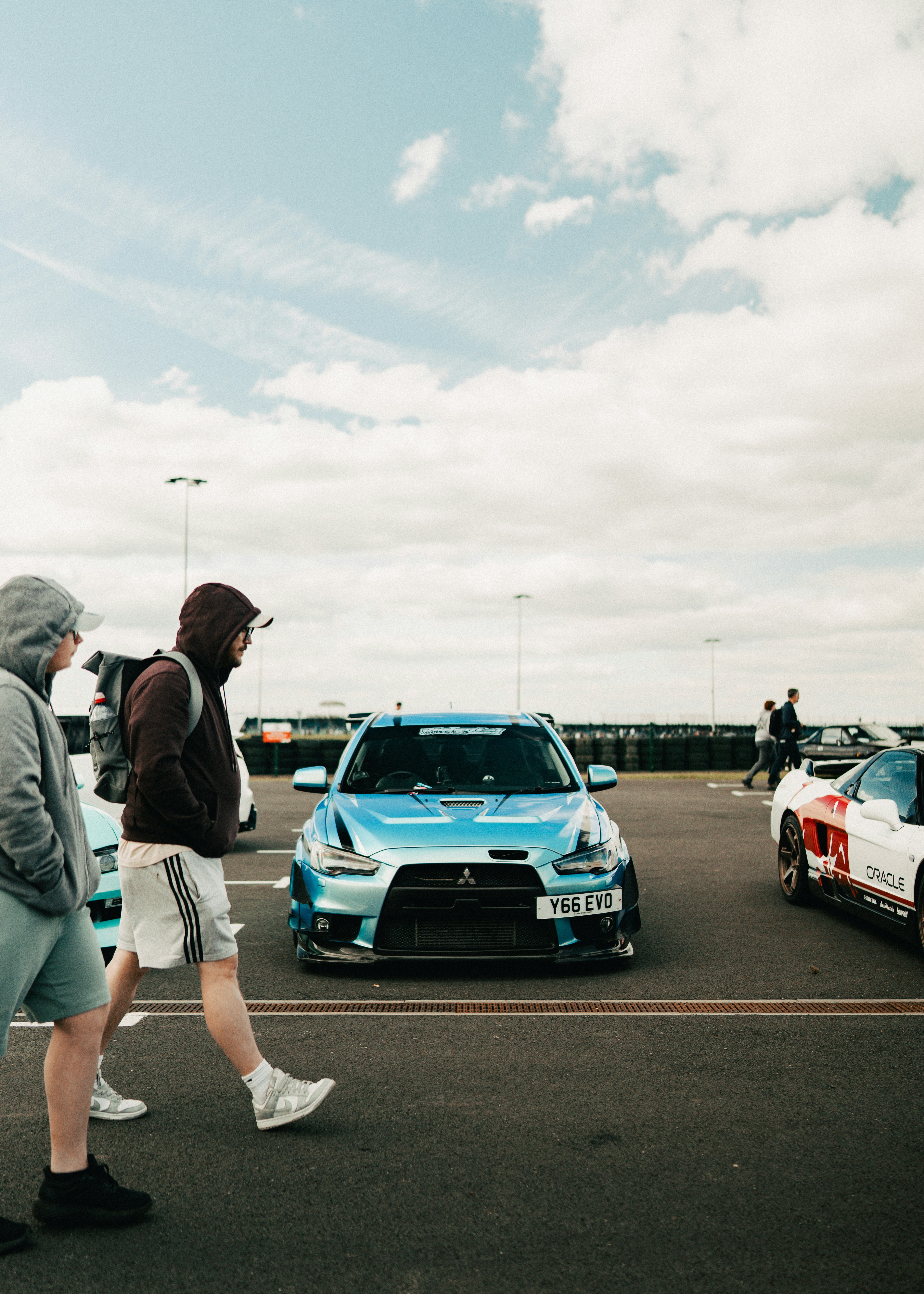 People walk past a blue sports car at an event