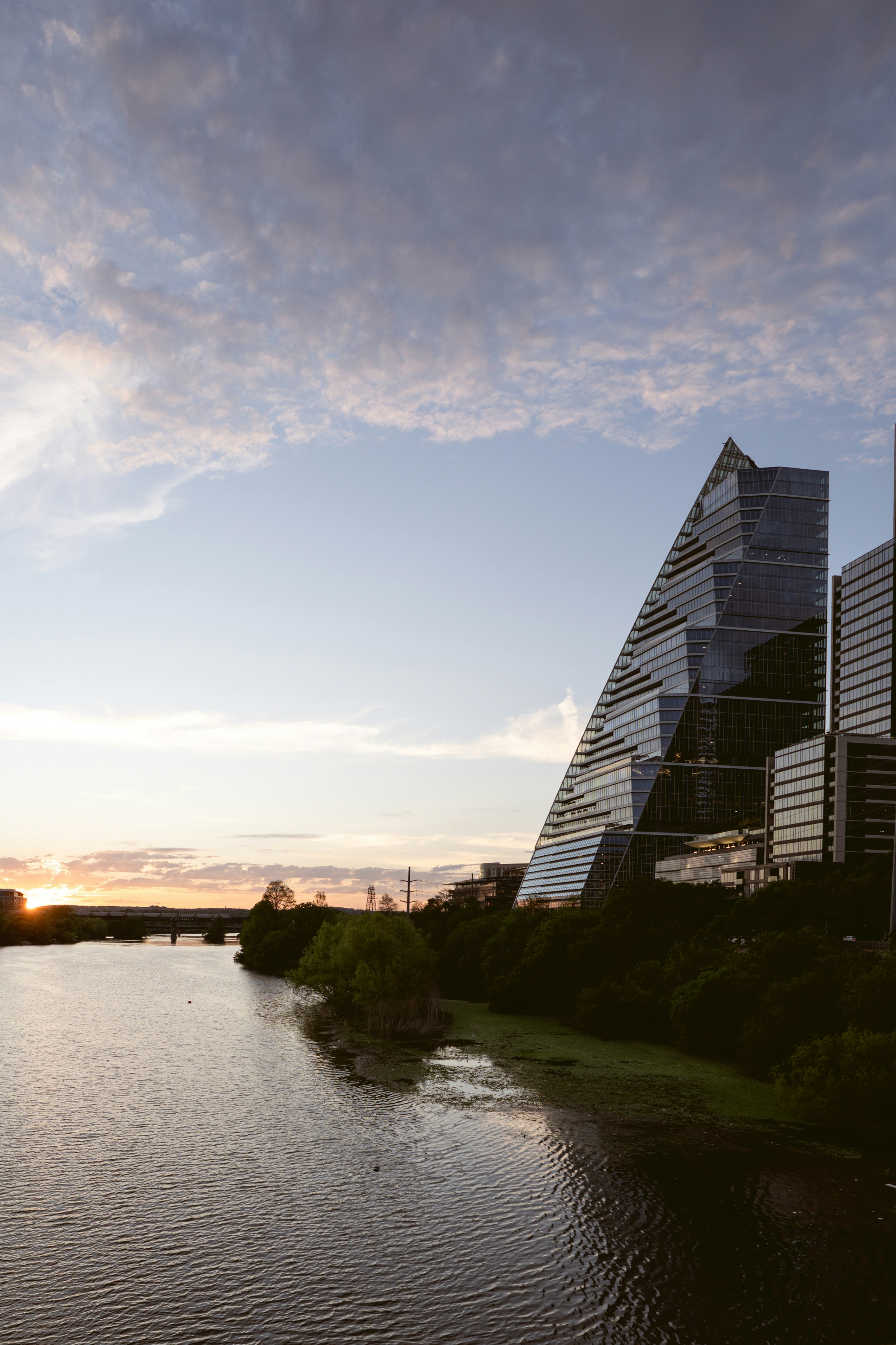 Modern skyscraper beside a river at sunset