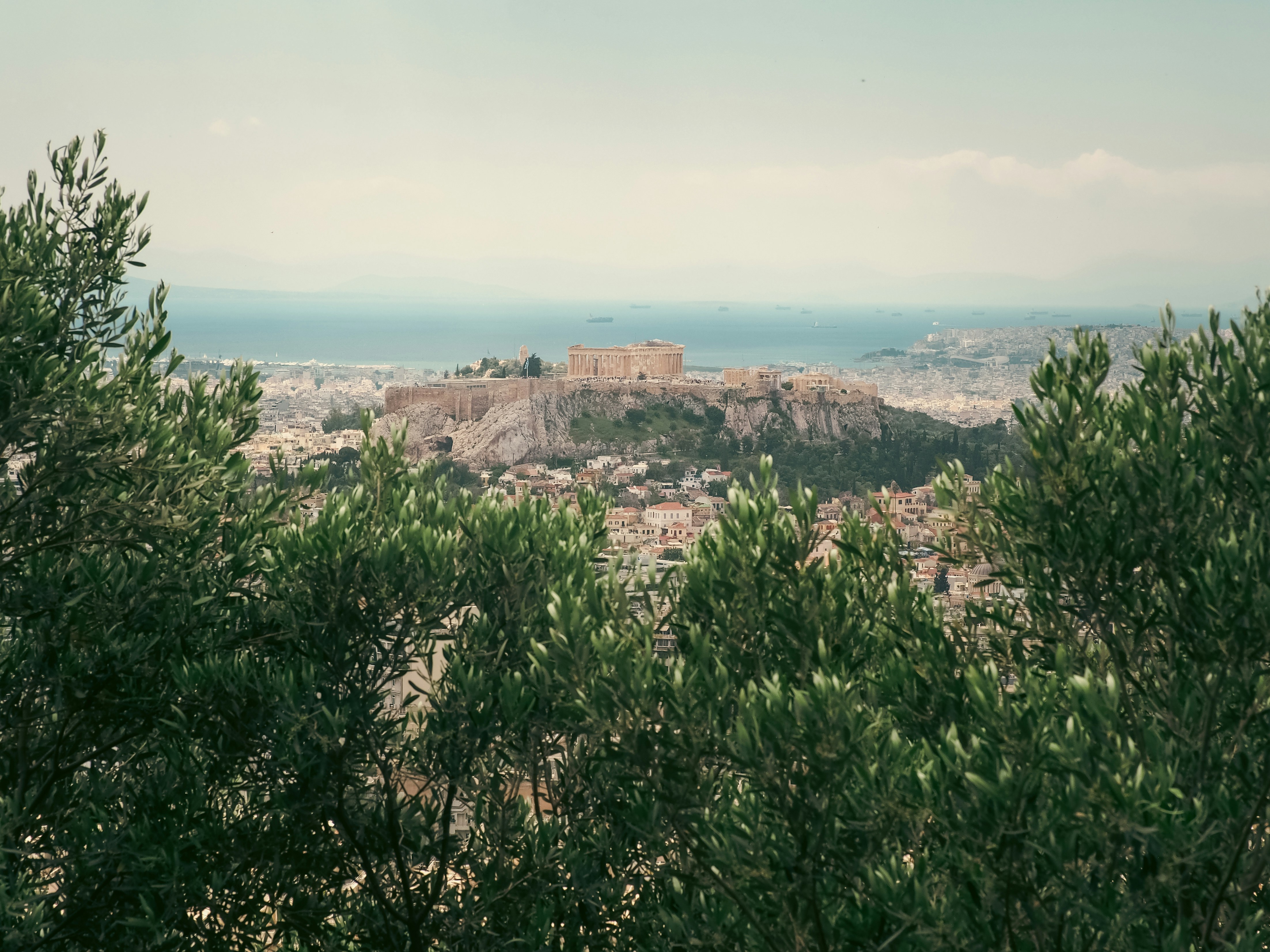 Ancient ruins on a hill overlooking a city and sea.