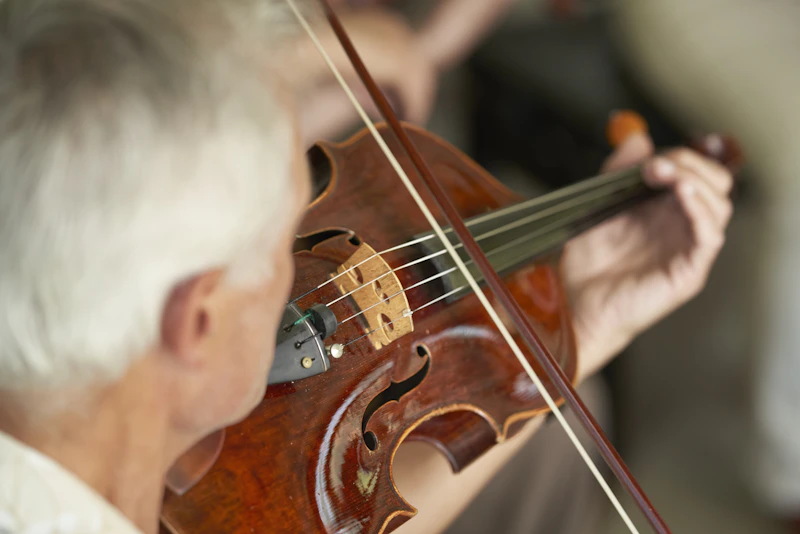 Adulto mayor tocando violín en una sesión de musicoterapia