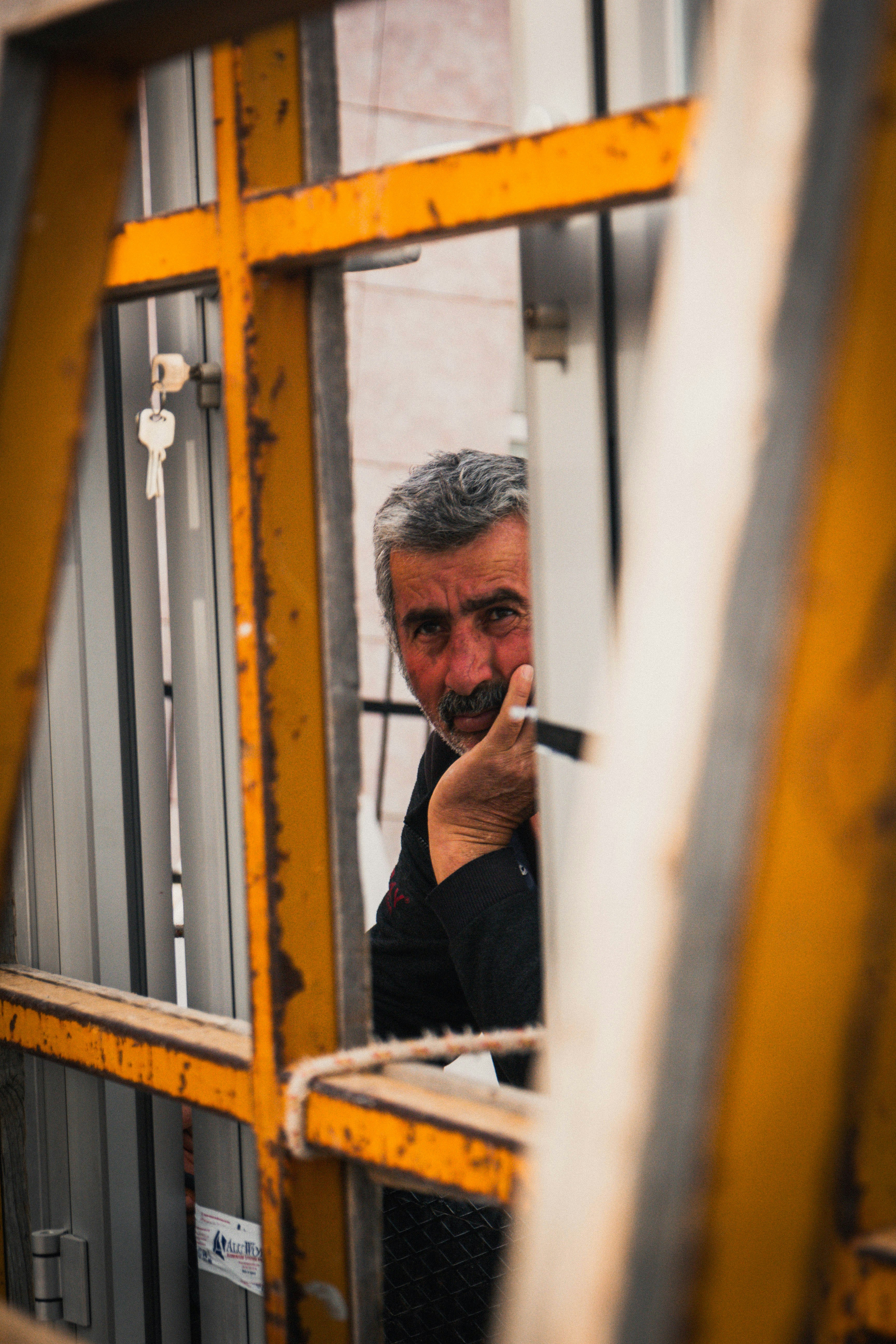Man peeking through a yellow metal structure.