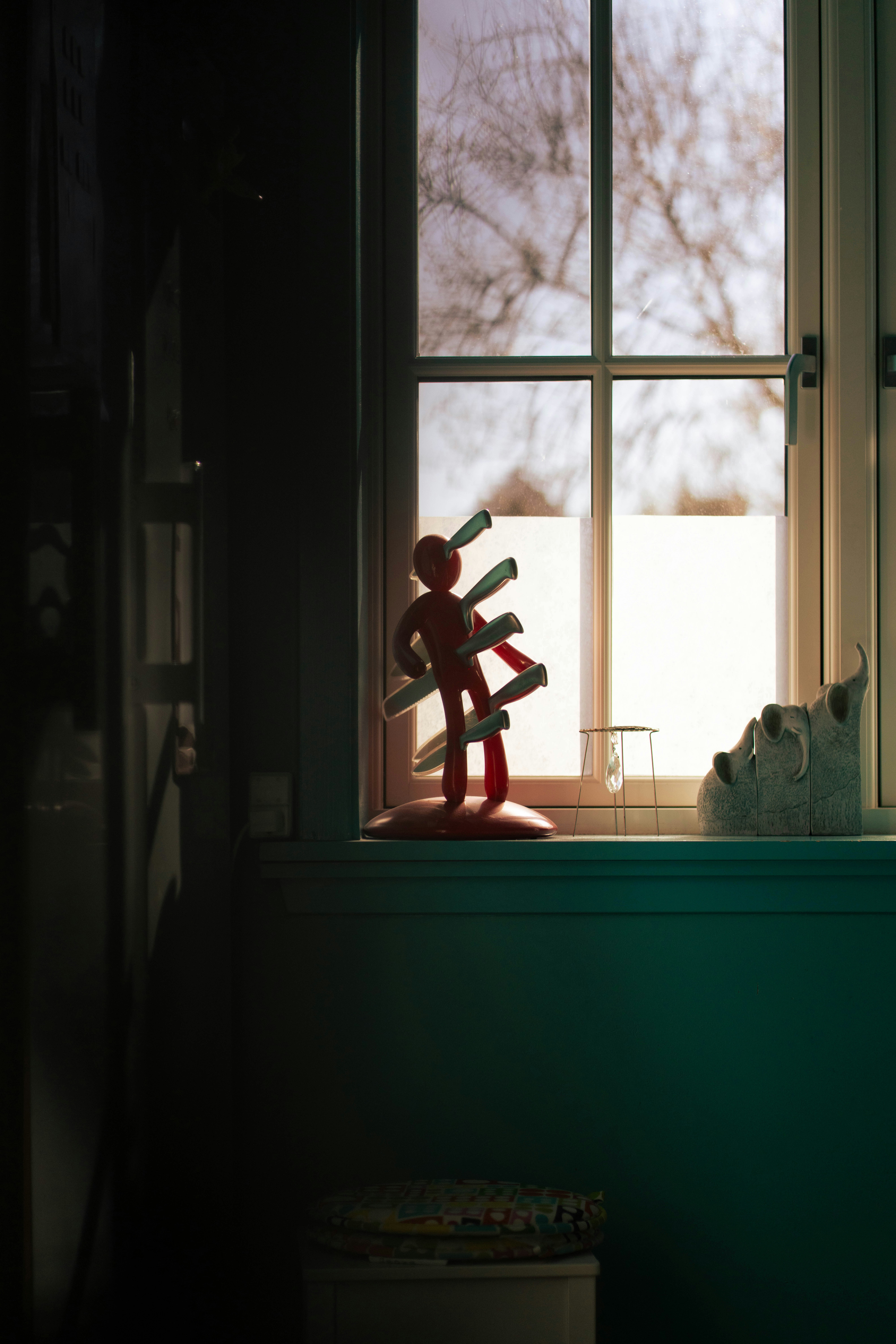 Figurita roja con cuchillos en la ventana