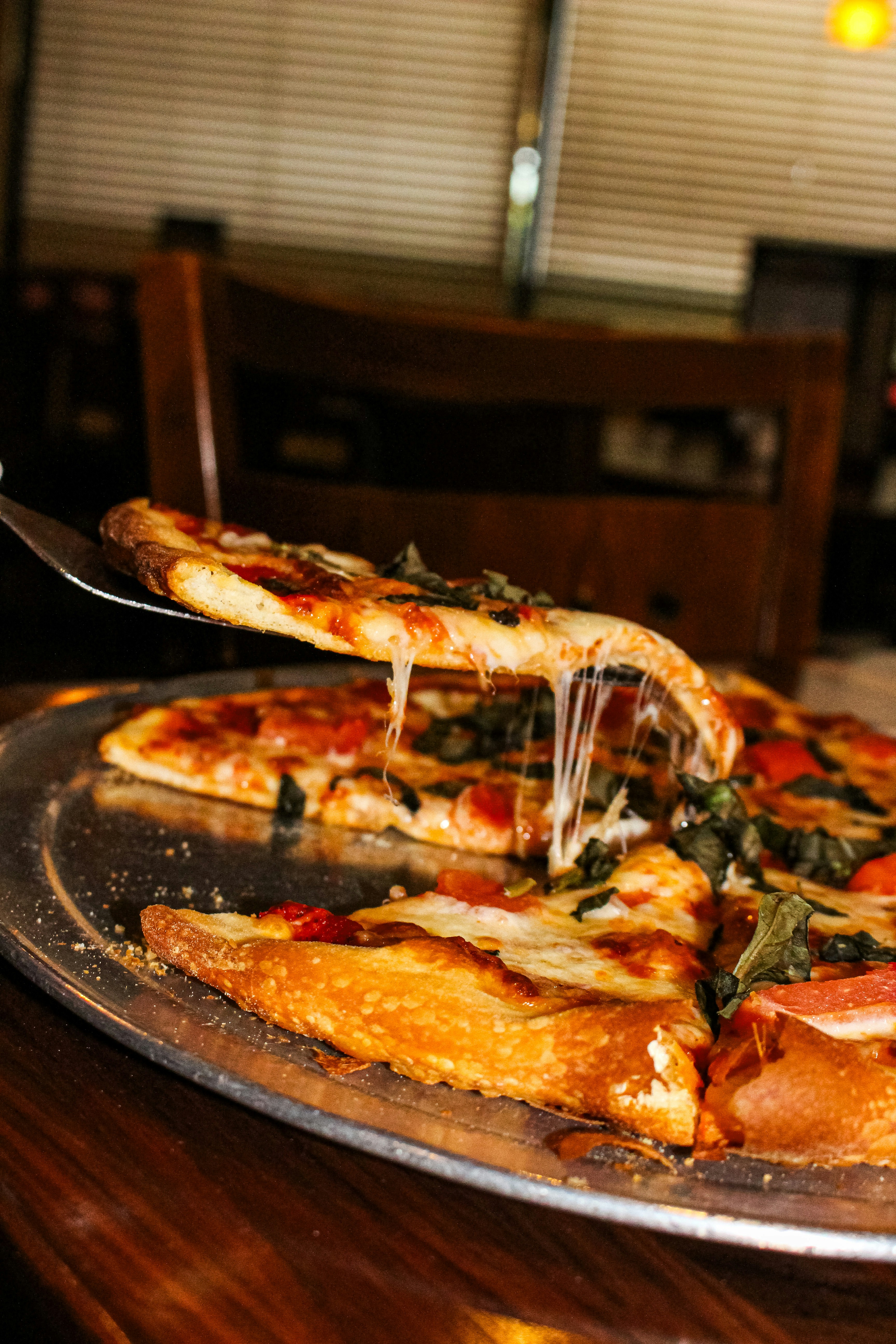 A slice of pizza being lifted from a whole pizza.