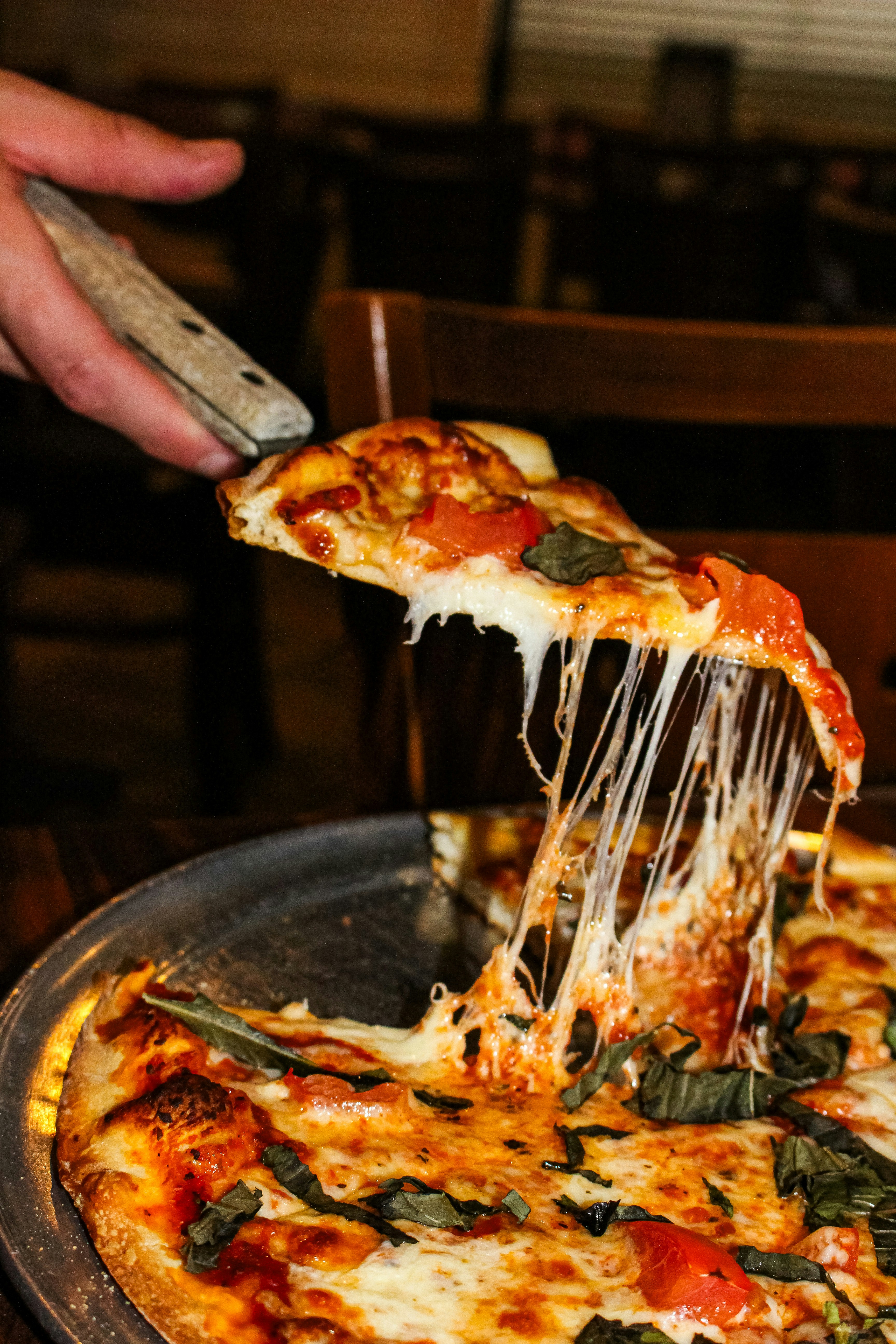A slice of pizza with melted cheese being lifted