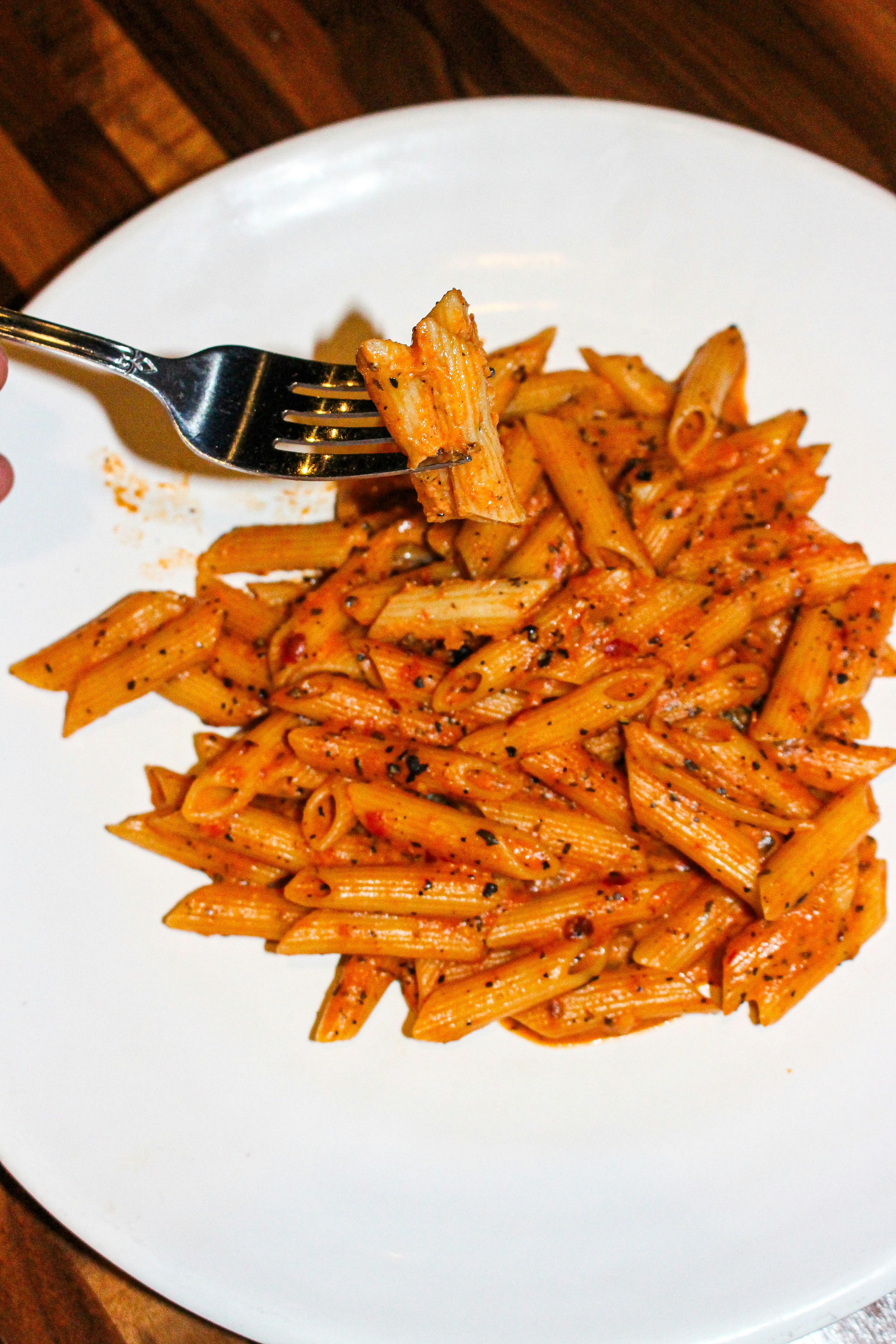 Penne pasta with tomato sauce and herbs on a plate.