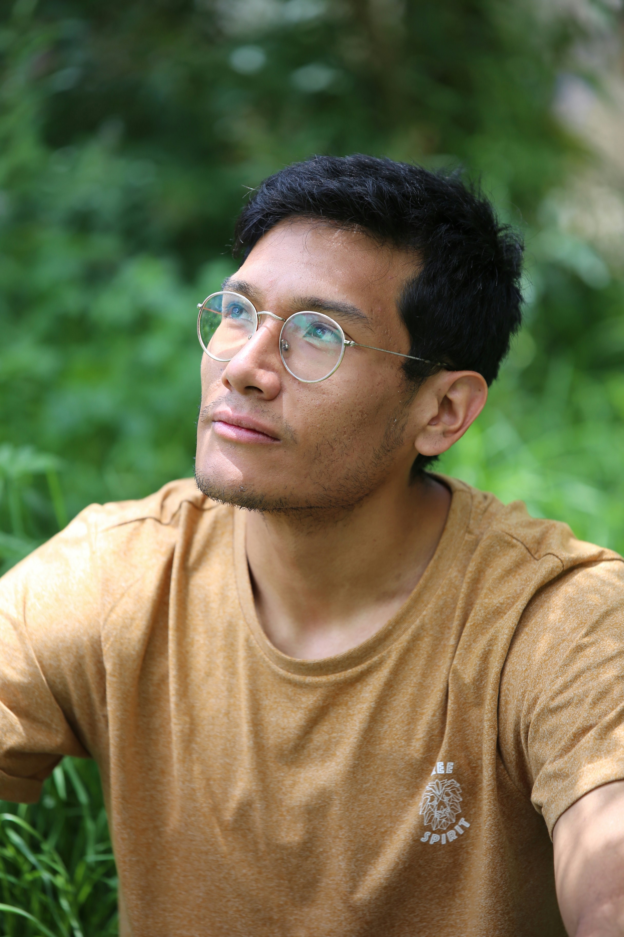 Man in brown shirt and glasses looking up outdoors