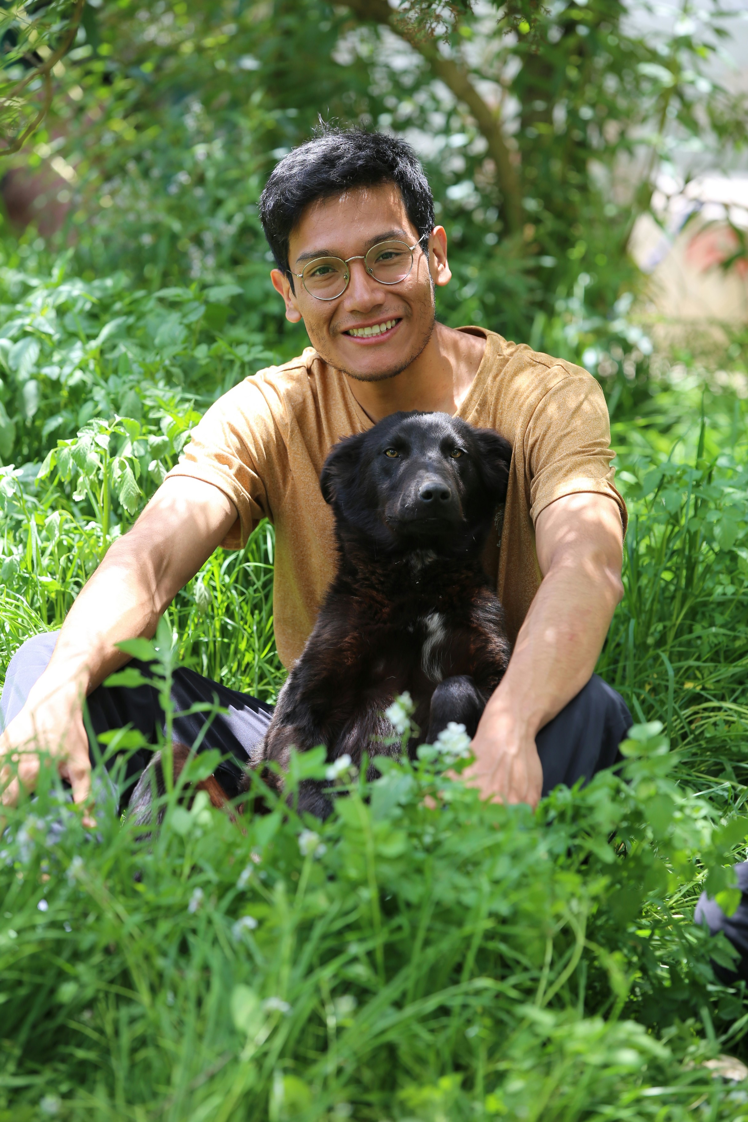 A man and his black dog sitting in green grass