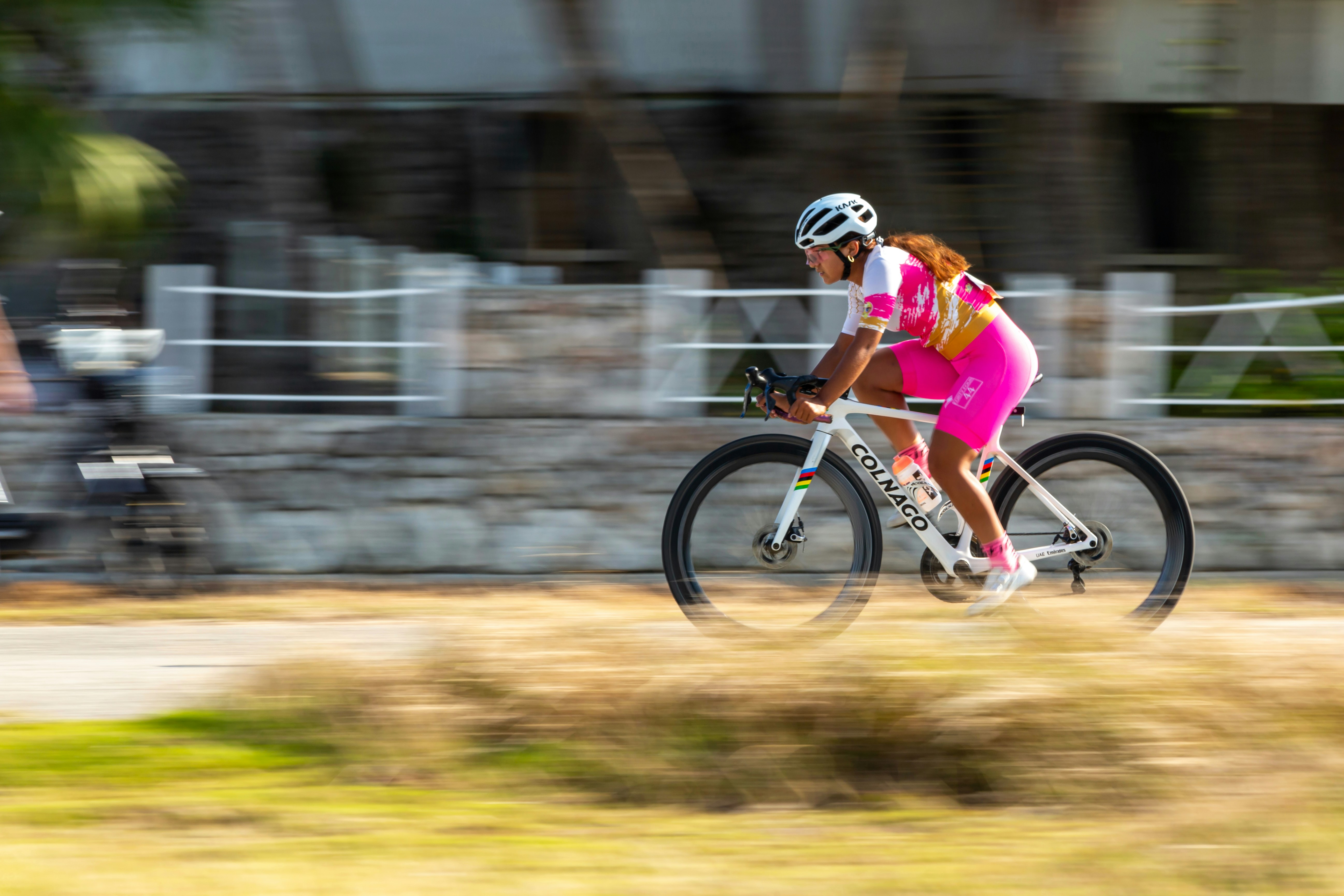 Donna in abito rosa da ciclista va veloce in bicicletta.