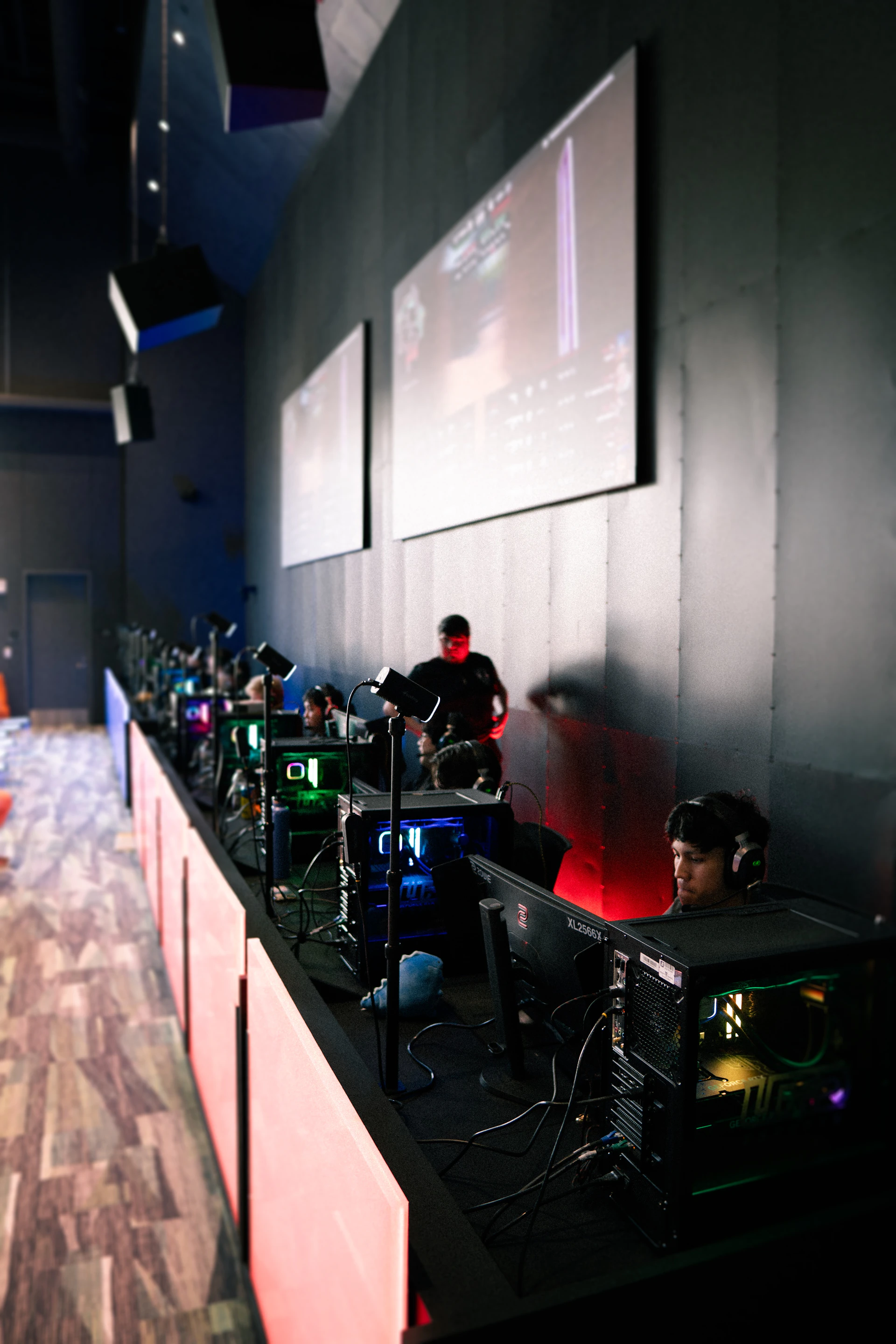 People play video games in a dimly lit esports arena.