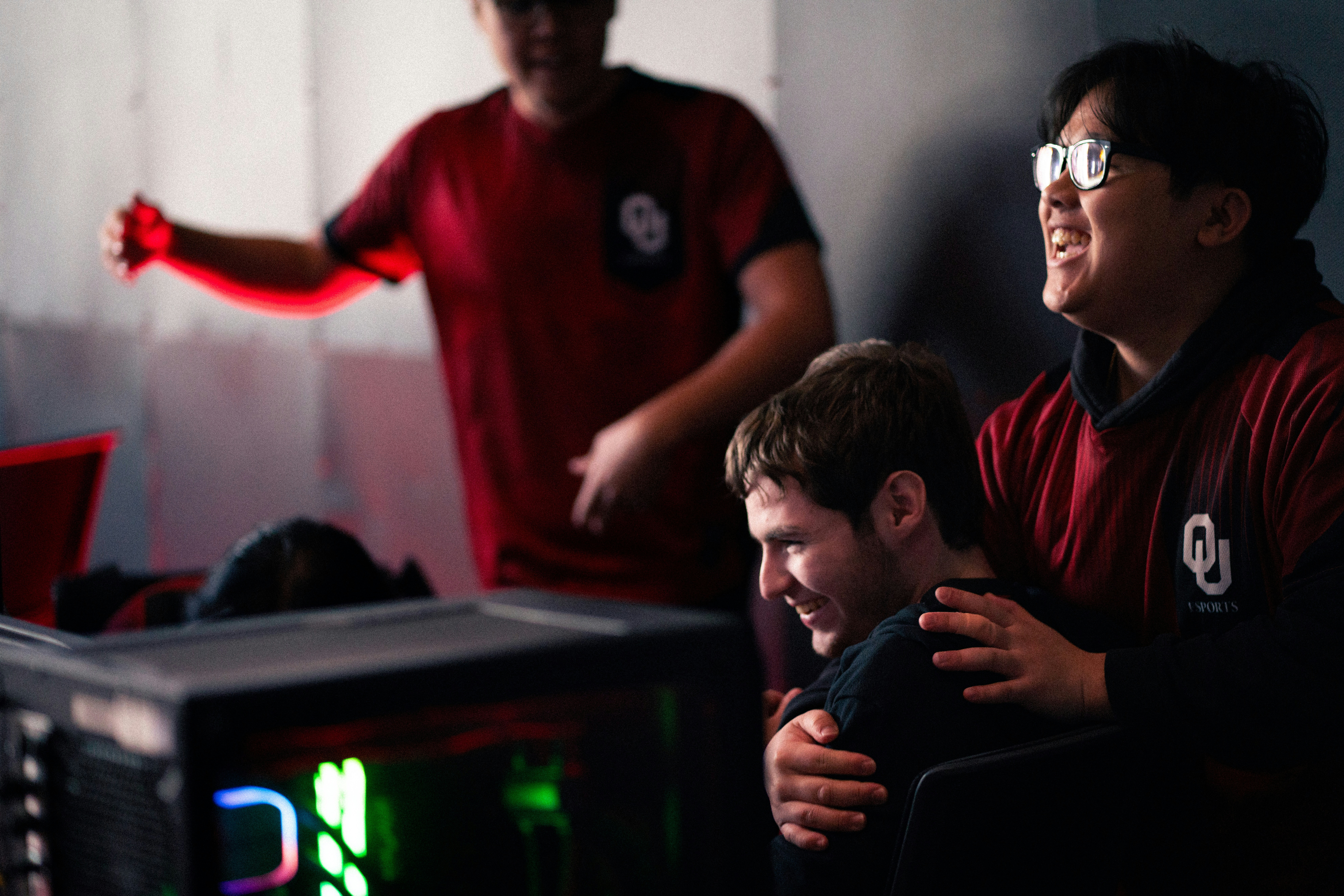 Three men in red shirts watching a computer screen