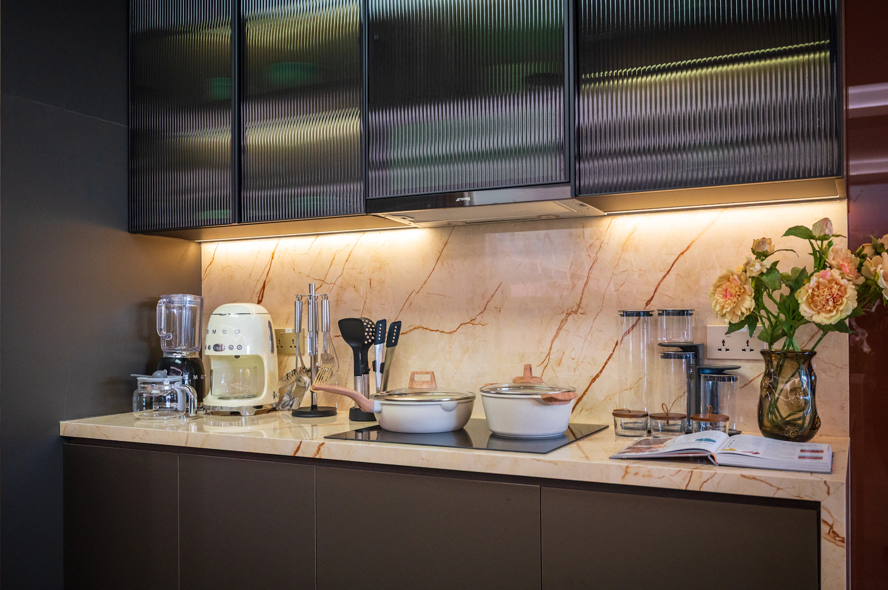 Modern kitchen counter with countertop appliances, cookware, utensils, and an open recipe book
