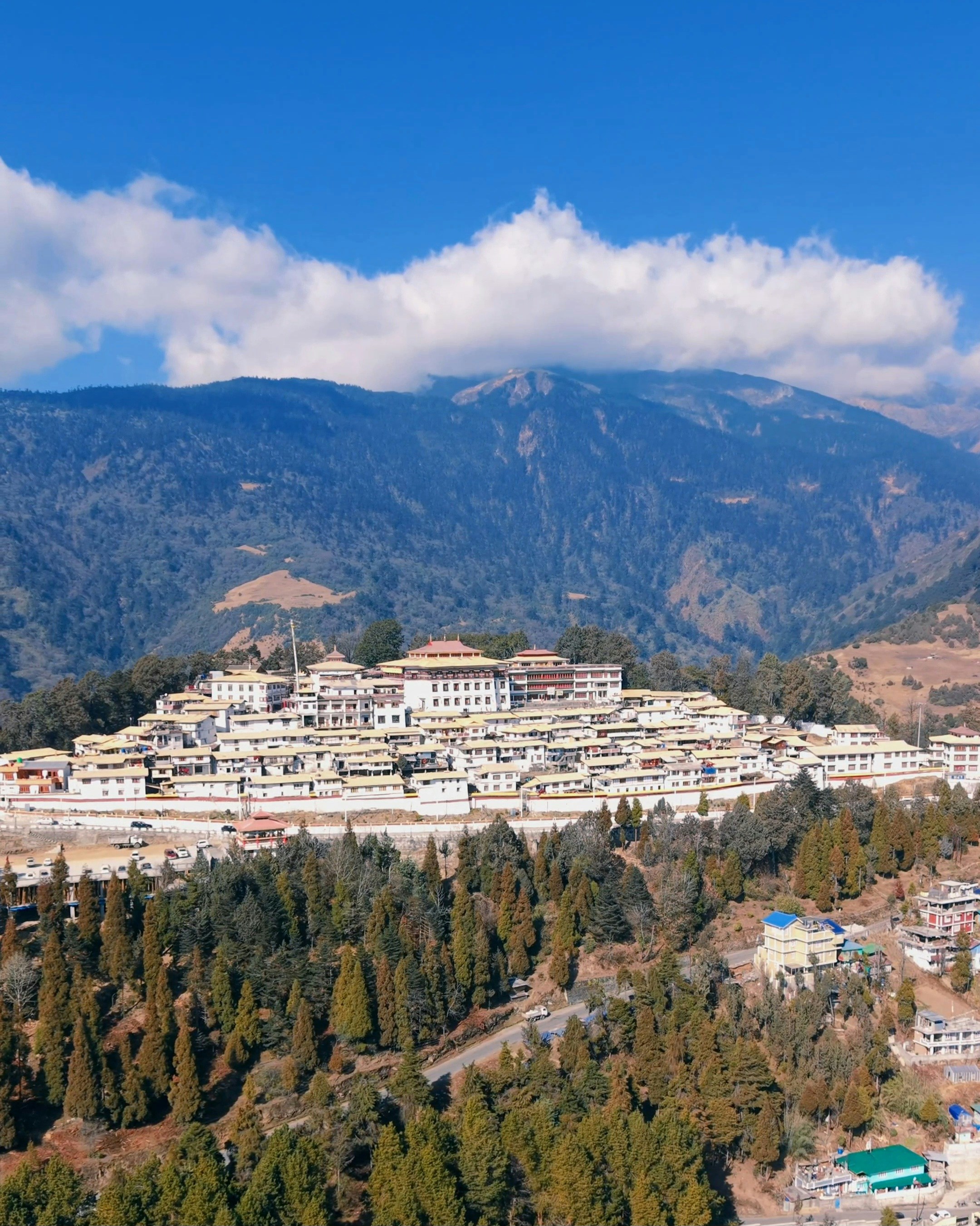 Monastery complex nestled on a hillside with mountains behind