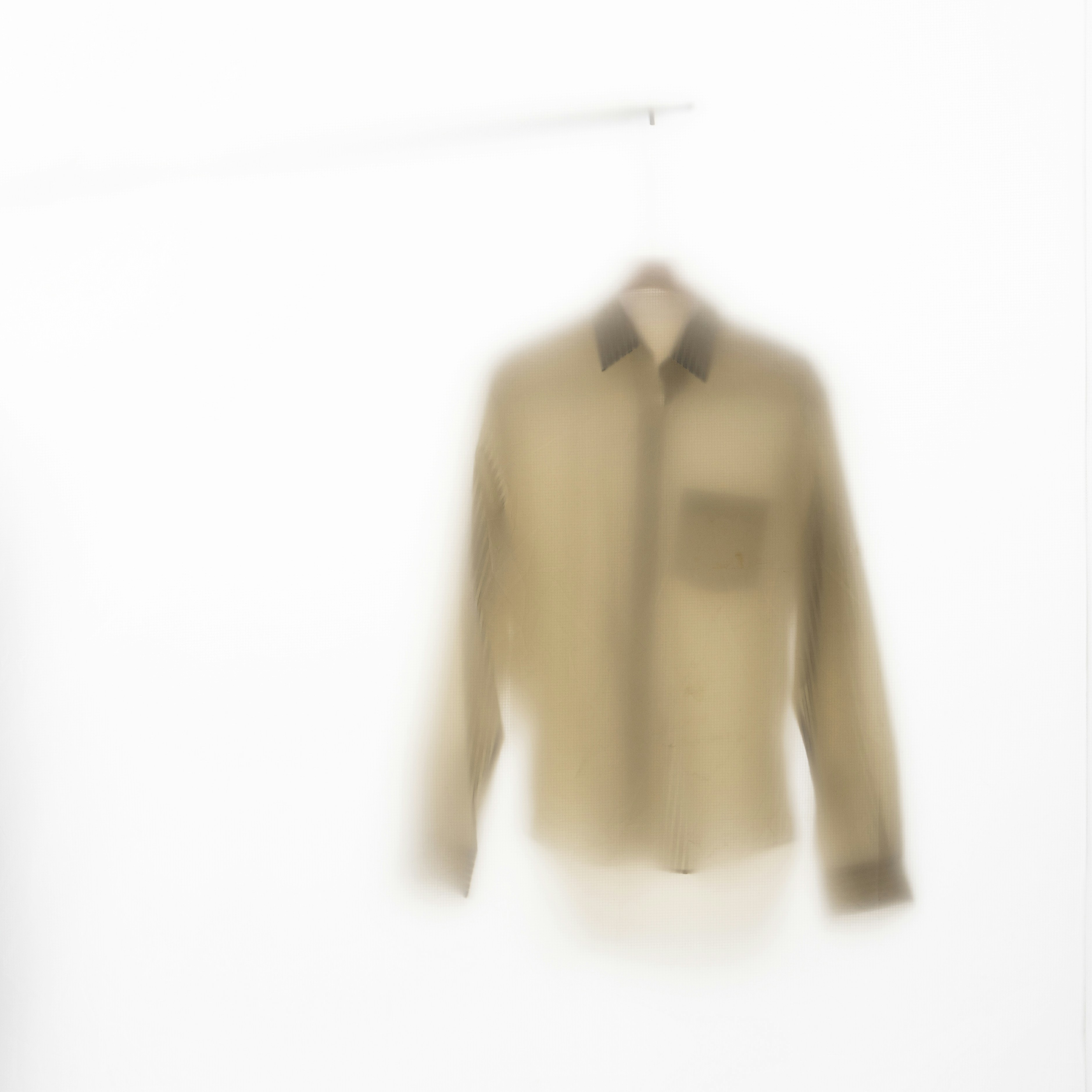 Una camicia con colletto beige appesa a una gruccia.