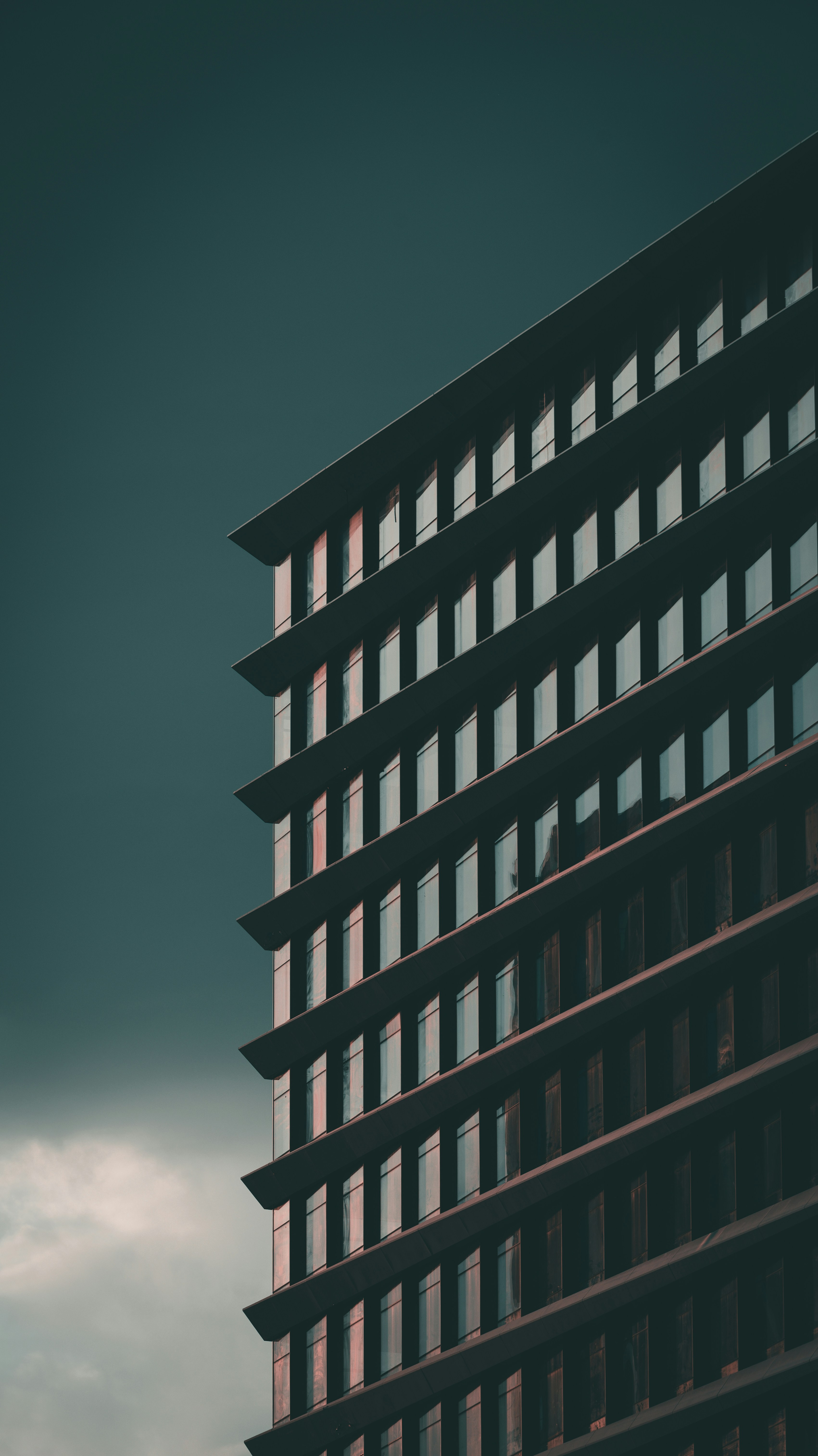 Fachada moderna de edificio con ventanas repetidas contra cielo oscuro