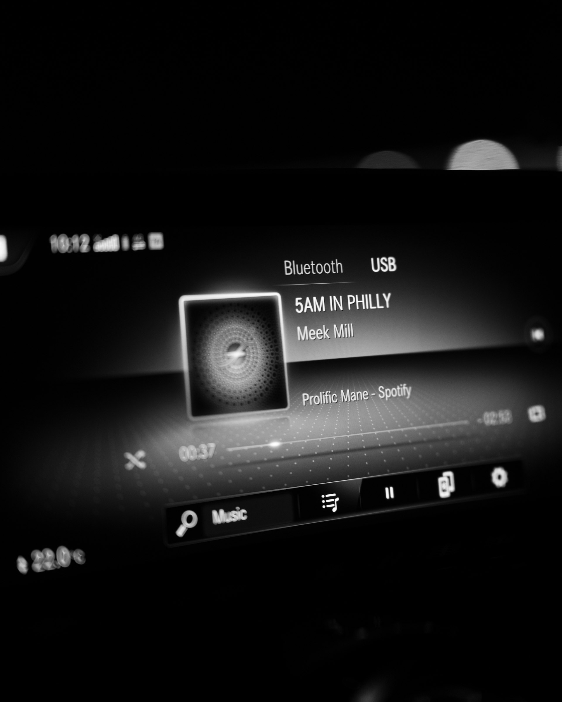 Modernes Car-Infotainment-Display mit Spotify-Musikplayer und blauen Bedienelementen im dunklen Autoinnenraum