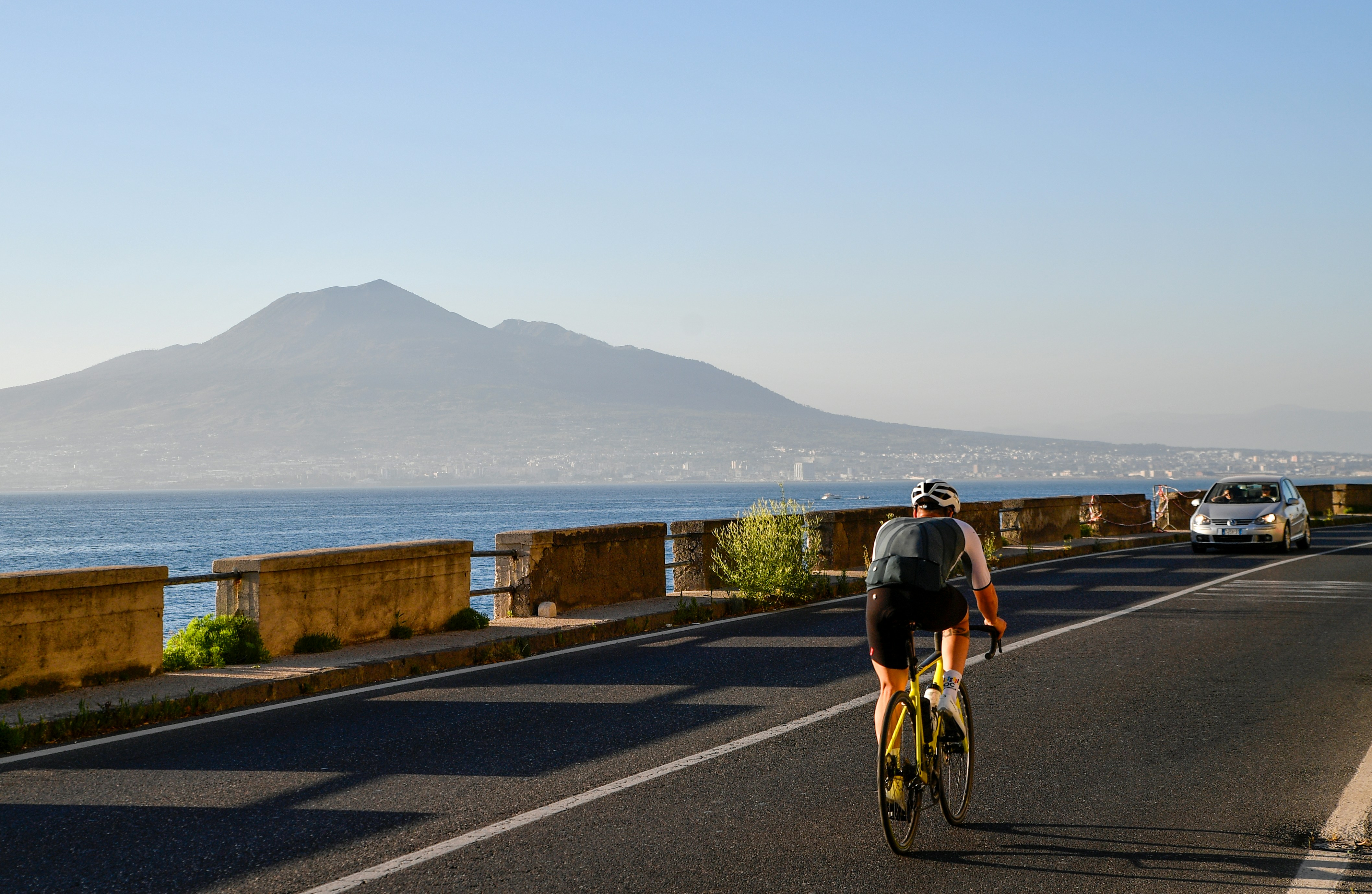 Cyclist rides on road with mountain and ocean view