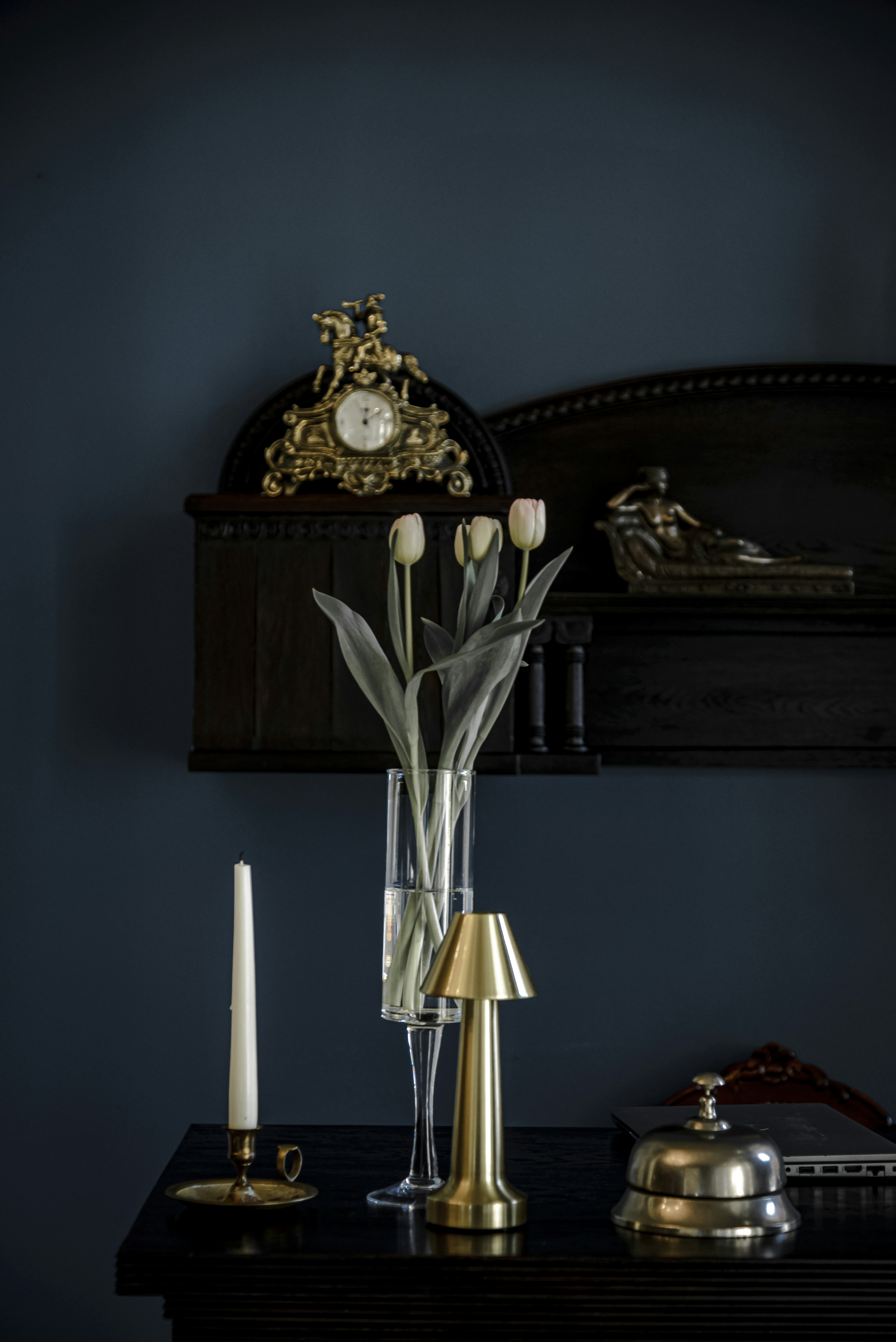 Eine Kerze, eine Vase mit Tulpen und eine Lampe auf einem Tisch.